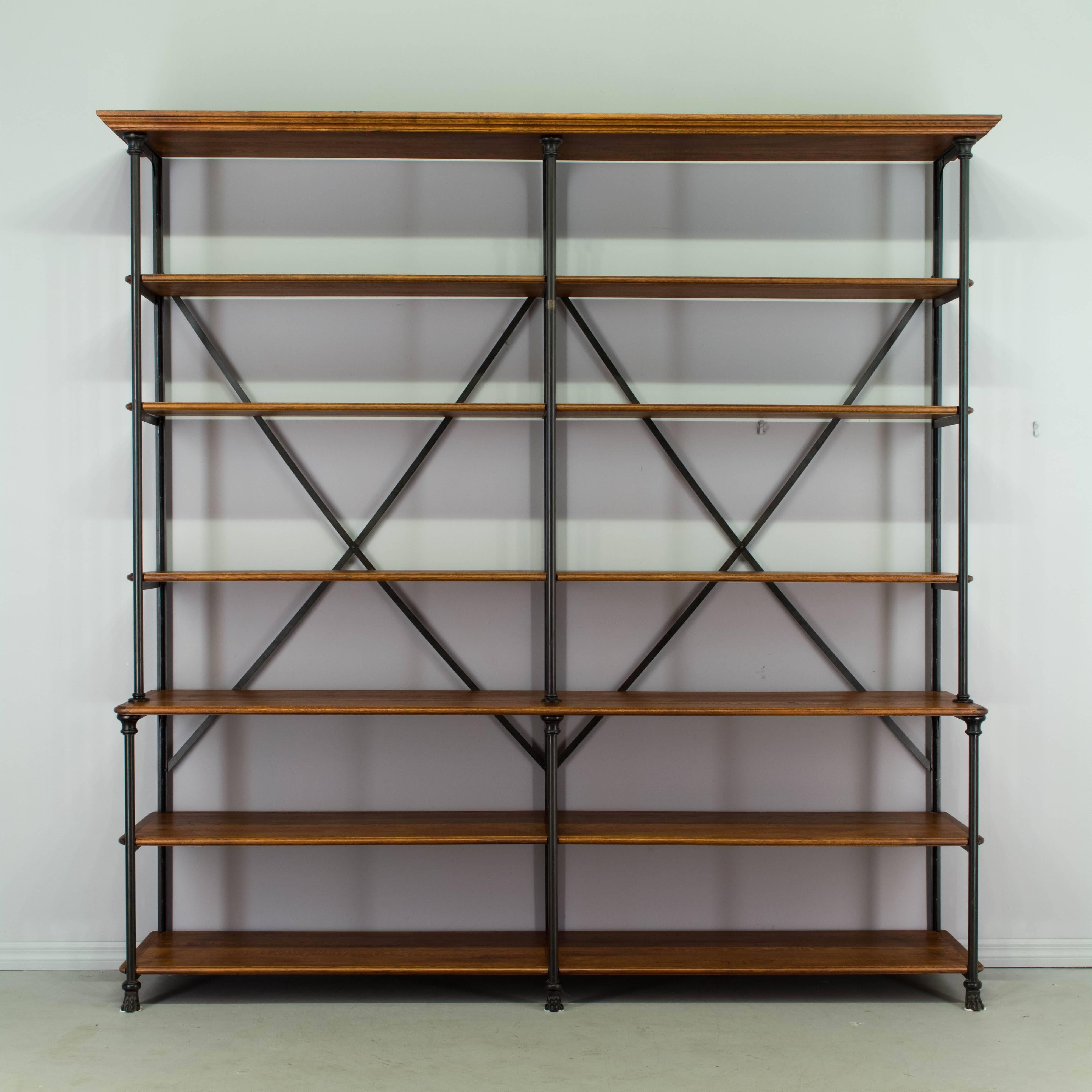 An Industrial étagère by Le Petit Parisien with iron mounted frame and shelves made of Eastern European oak. Very sturdy, heavy frame with X-shaped back supports and decorative cast feet. Subtly detailed, with cornice top and fitted shelves with