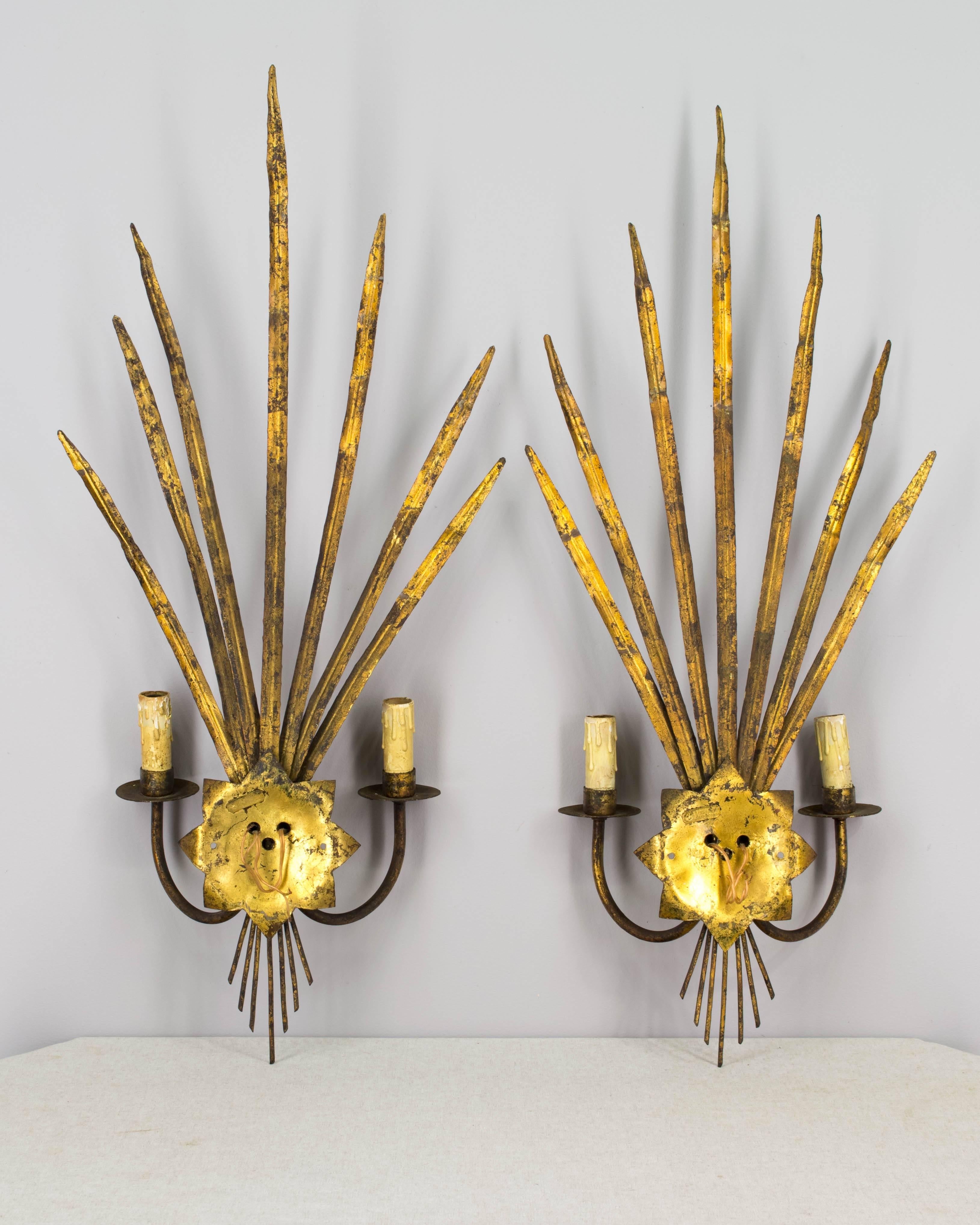 Pair of 20th century Spanish gilt metal sconces with palm leaf forms and two-light candlesticks. Old wiring with European sockets, these will need to be rewired. Metal tag on back reads: Ferro color made in Spain.