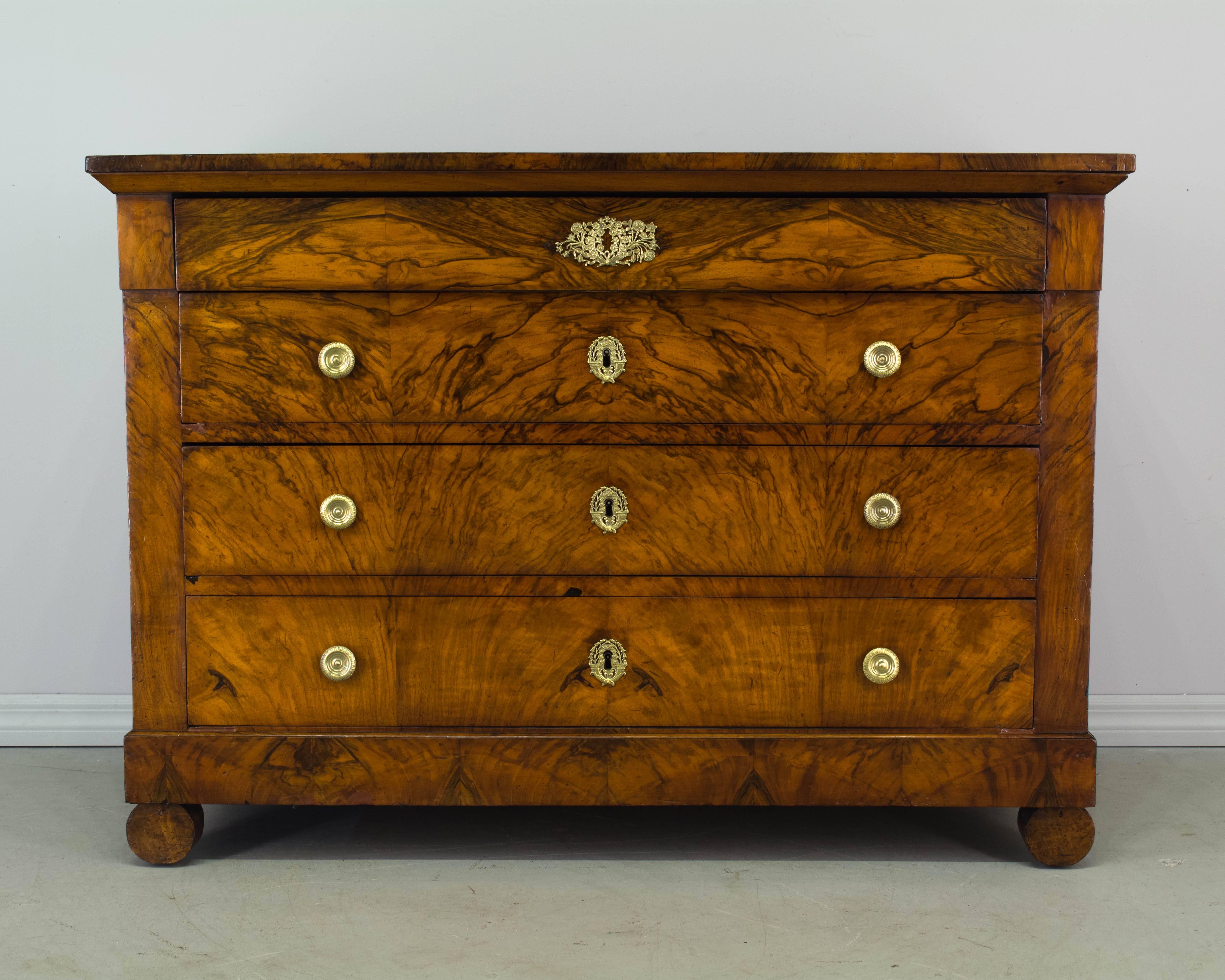 A fine 19th century Restauration Period commode with beautifully patterned bookmatched veneer of walnut on front, sides and top. Four dovetailed drawers provide ample storage. French polish finish. Oak as a secondary wood. Locks are present, but