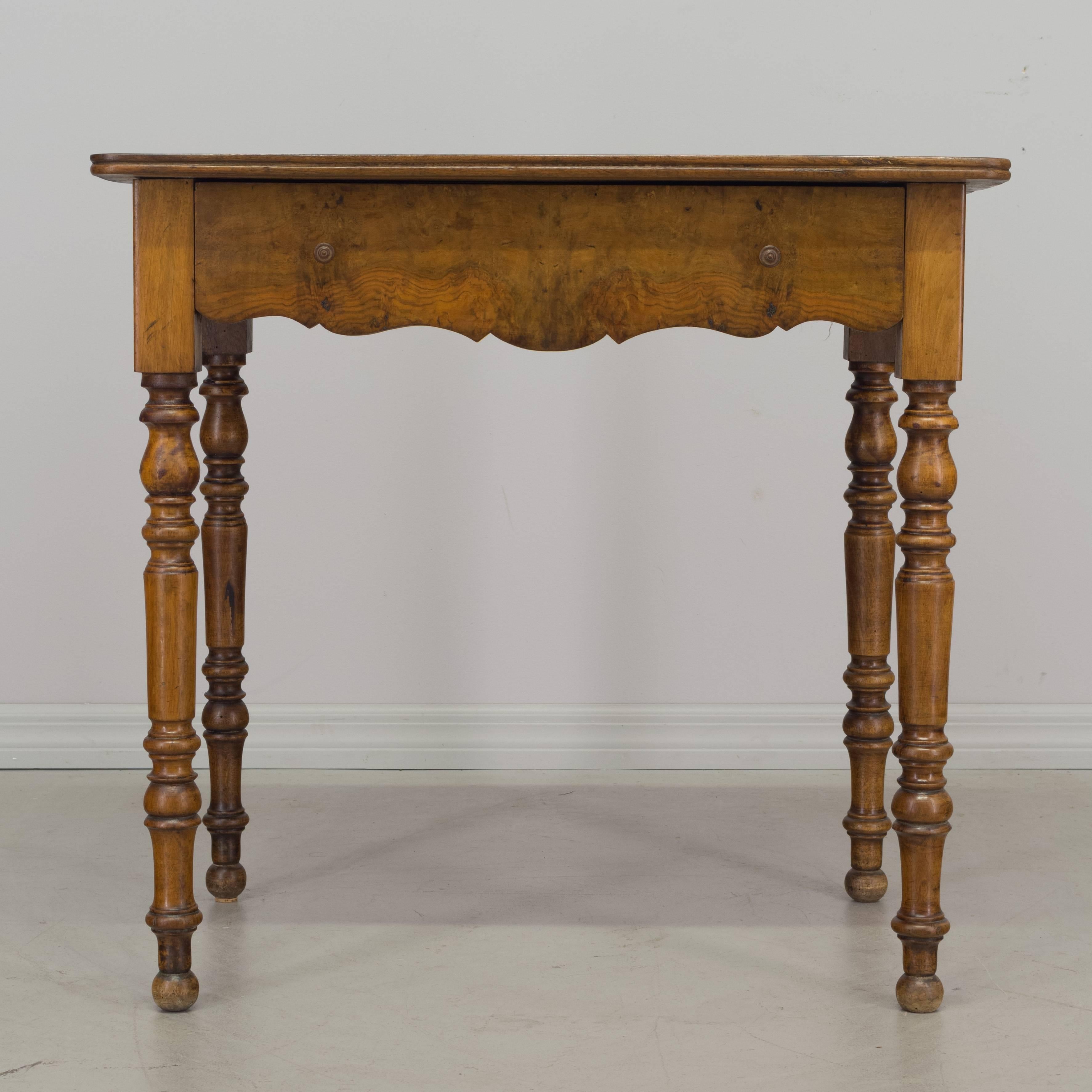 19th century Louis-Philippe side table made of solid walnut with fine turned legs. Single dovetailed drawer with bookmatched front. Beautiful swirling pattern in the wood grain of the tabletop.