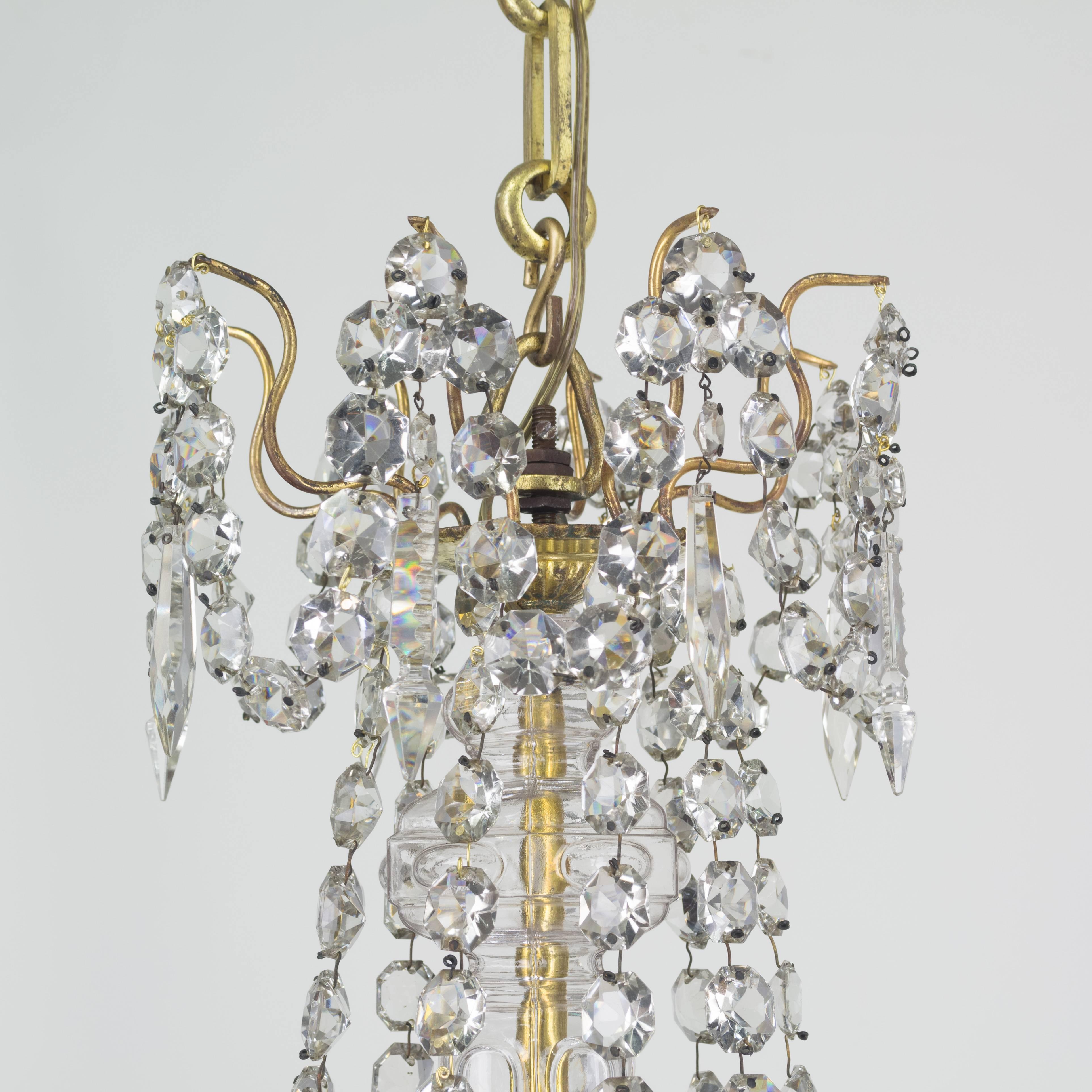 A fine late 19th century French gilt bronze and crystal nine-light chandelier with faceted jewel chains and hanging crystal prisms. Crown with swags and hanging prisms, a waterfall drape connecting to nine upswept candle arms with glass bobeches.