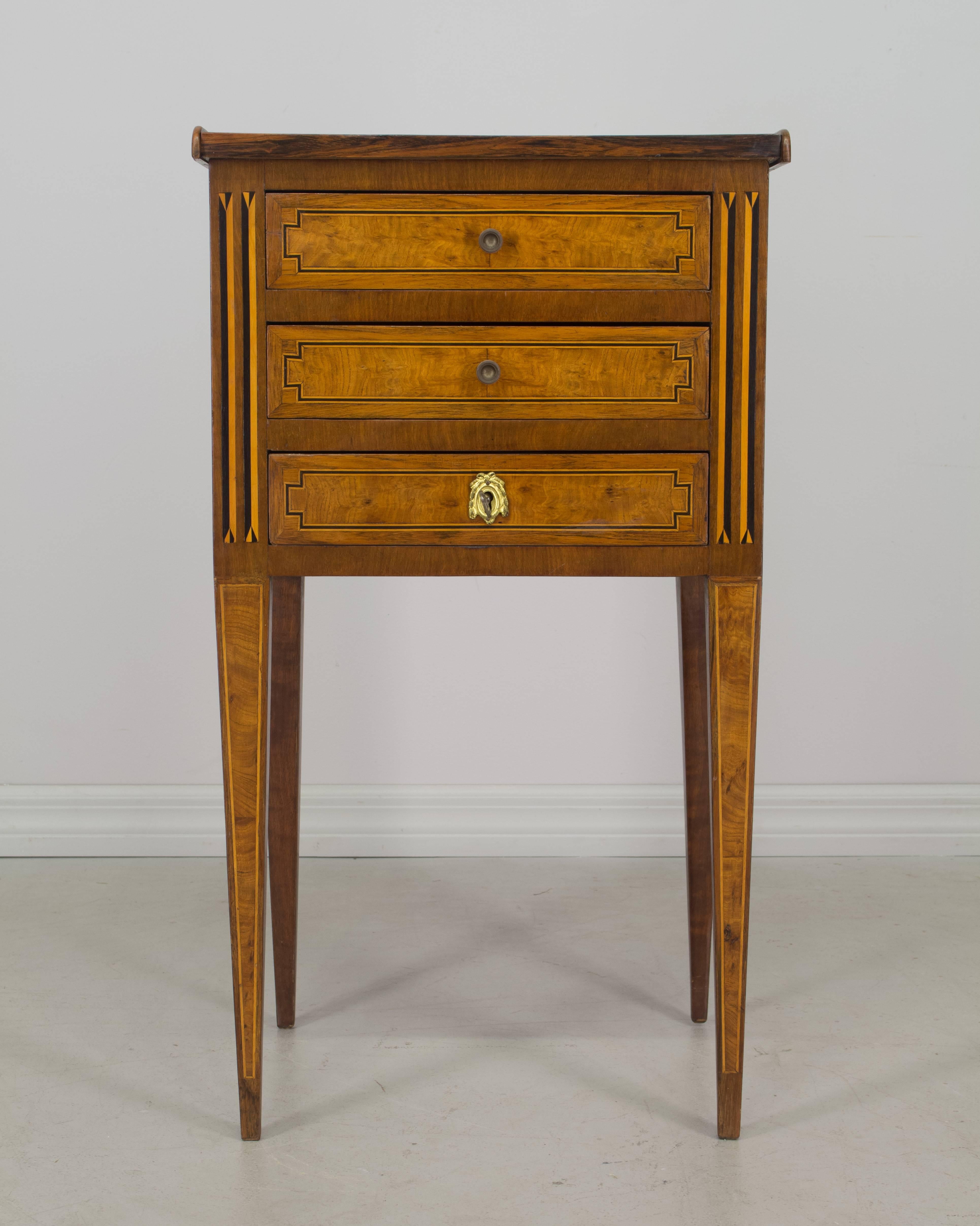 Louis XVI style marquetry side table inlaid with various veneers including burled walnut, mahogany and maple. Three dovetailed drawers with working lock and key. French polish finish. Oak as a secondary wood.