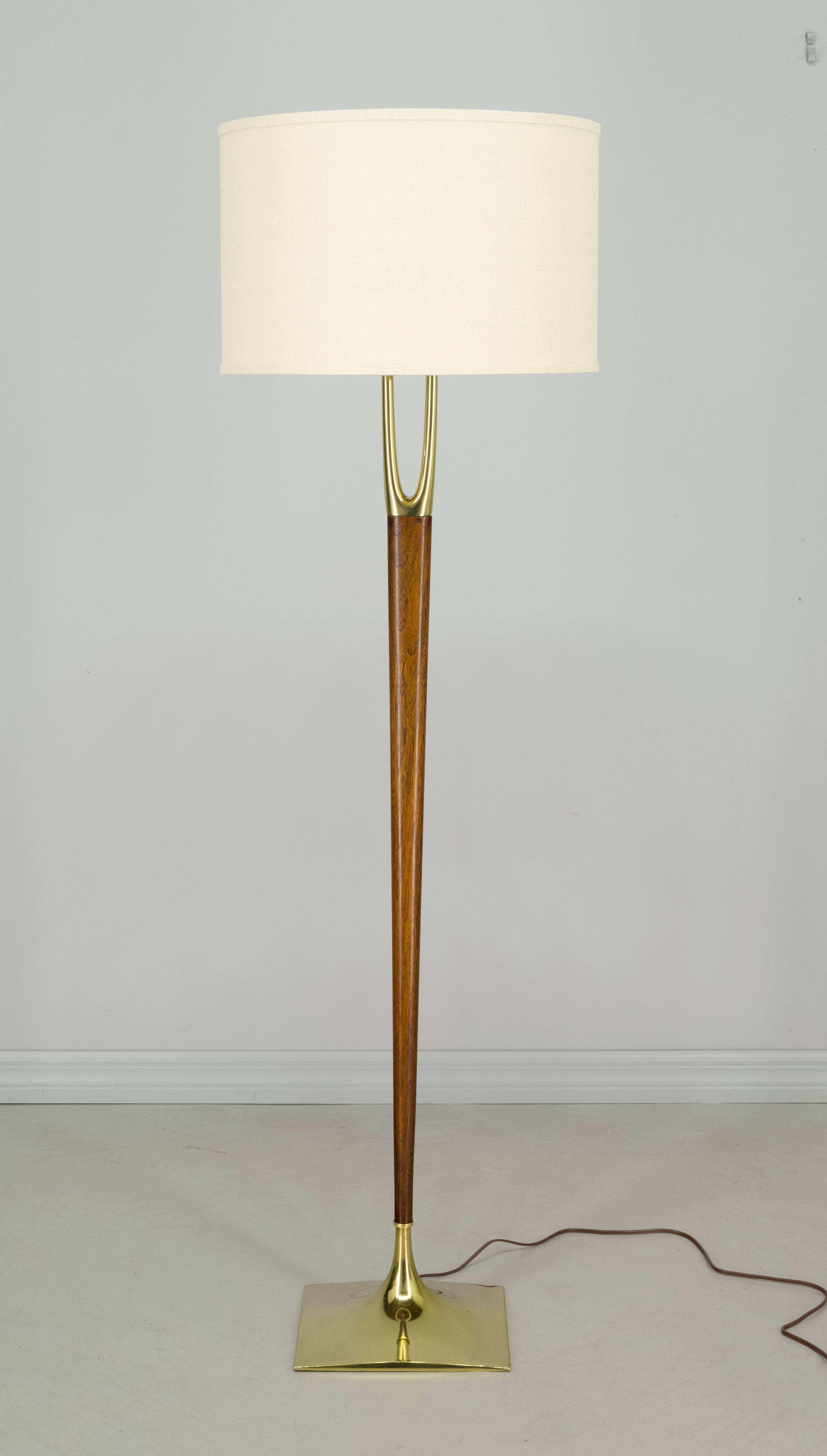 Iconic, sought after Mid-Century Modern floor lamp designed by Gerald Thurston and made by the Laurel Lamp Company. Solid walnut center post with beautiful wood grain. Brass-plated wishbone shaped prong at top and a brass-plated base. Rewired with