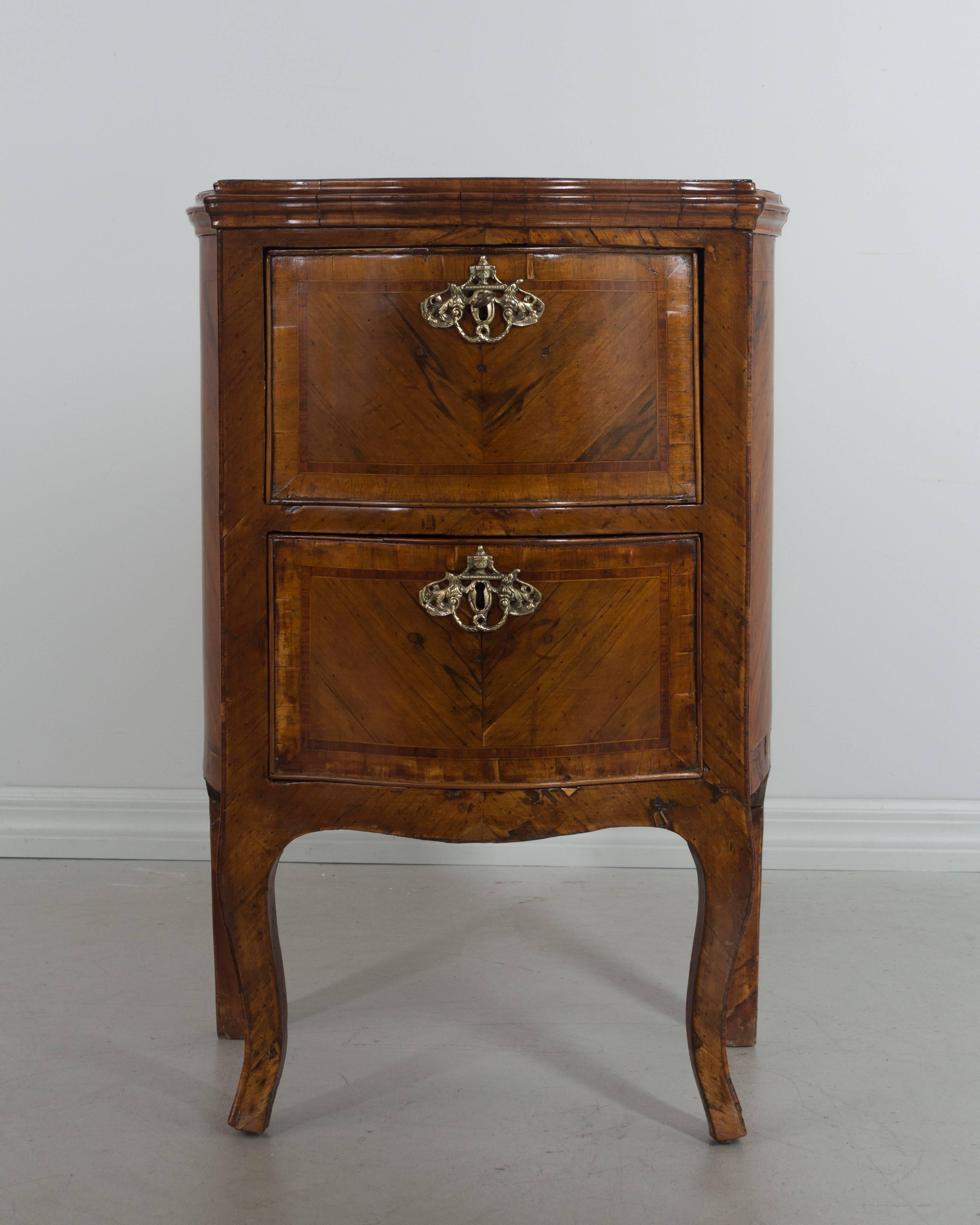 A small 18th Century Italian commode with serpentine front and curved sides, made of veneers of walnut. French polish finish. A nice size for use as a nightstand. New bronze hardware. Restoration on back legs.
More photos available upon request. We
