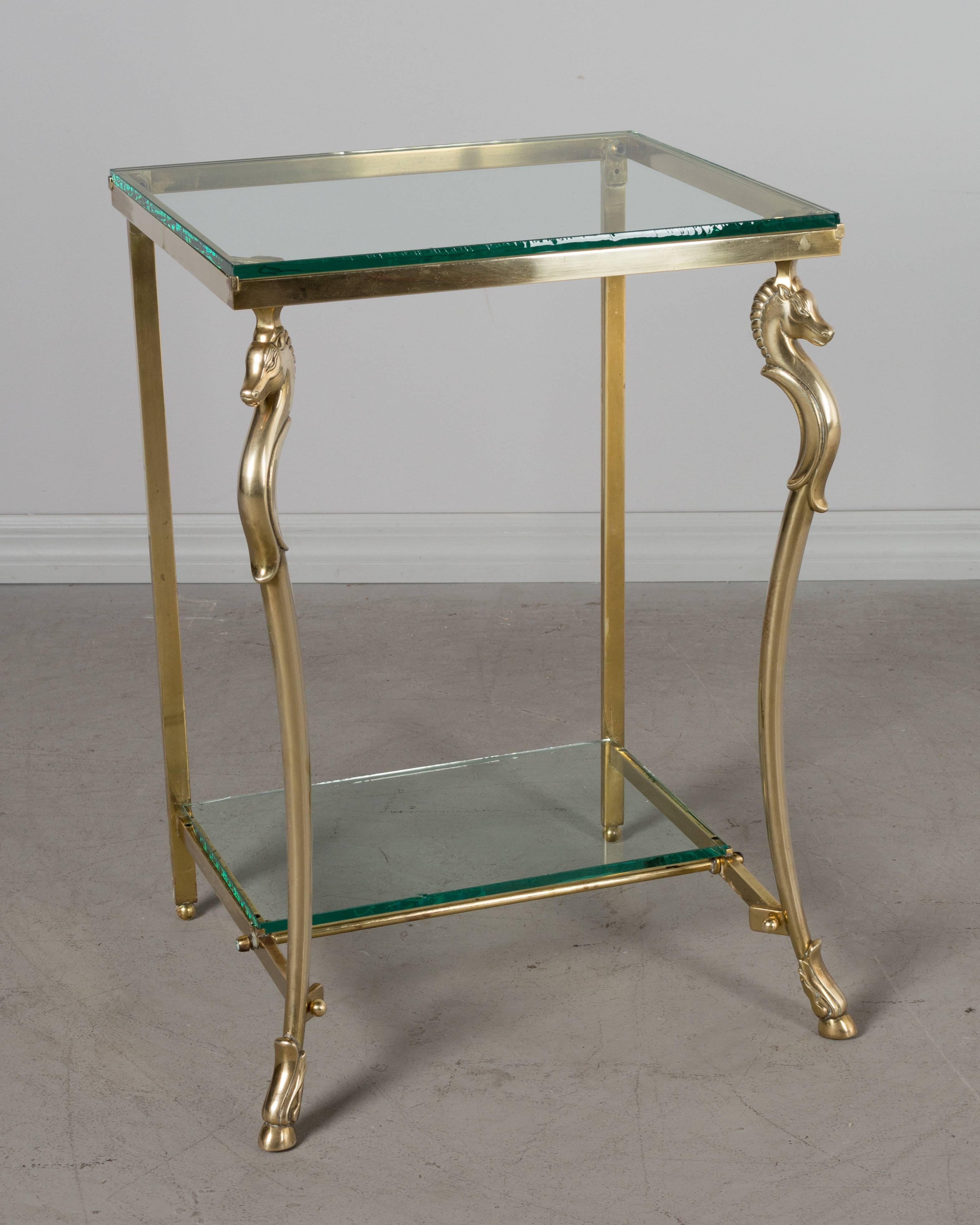 Pair of French Maison Jansen brass, horse motif side tables with glass tops and lower shelves. The brass is in excellent condition and has been polished but not lacquered. There are small chips to the corners an all four pieces of glass. There is