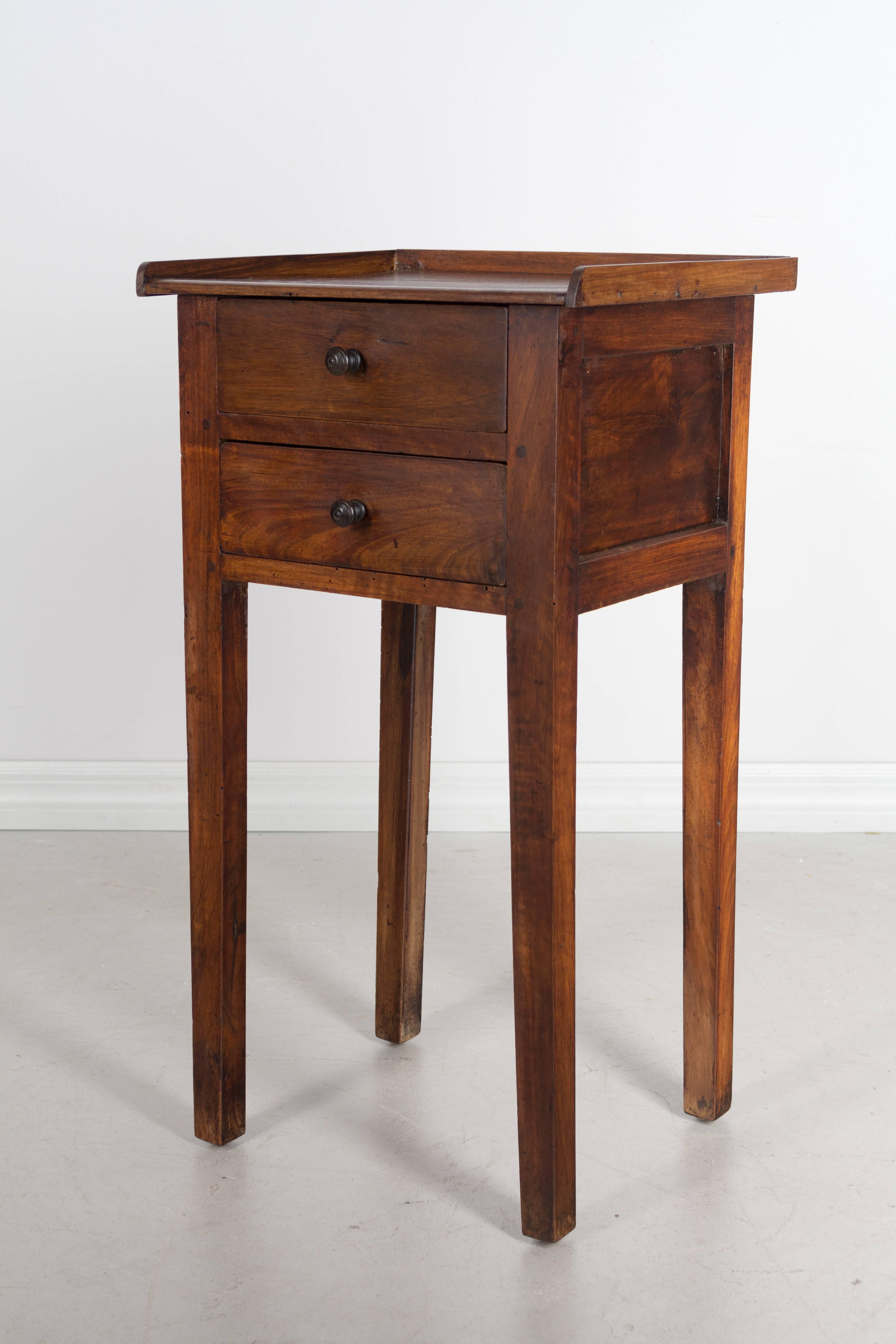 Small 19th century French side table with tapered legs and two dovetailed drawers. Made of solid walnut and finished on all sides. Pine as a secondary wood. Waxed finish.