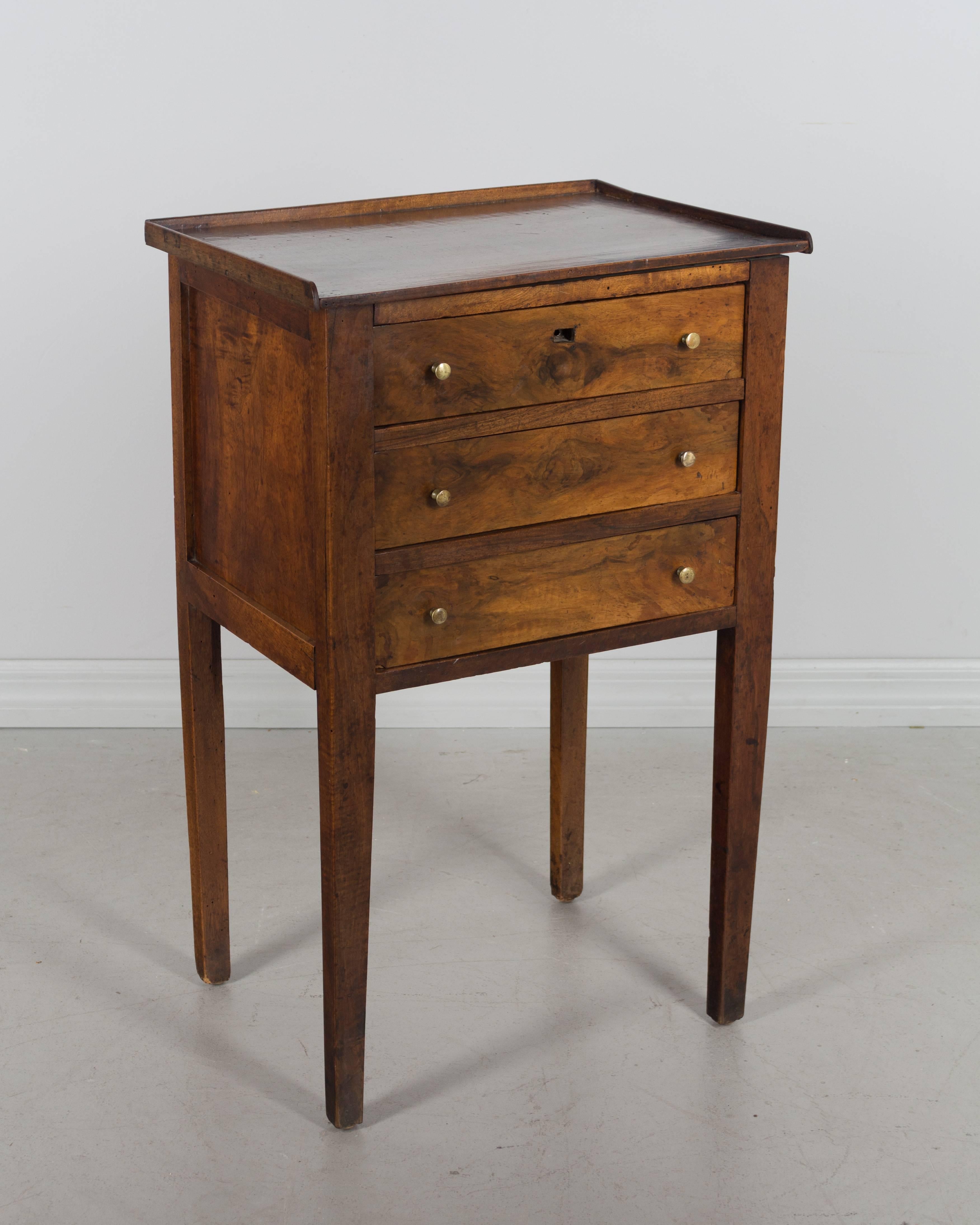19th century French Directoire side table with three dovetailed drawers. Made of solid walnut and finished on all sides. Pine as a secondary wood. Lock is present but there is no key. The escutcheon is missing on the top drawer.
