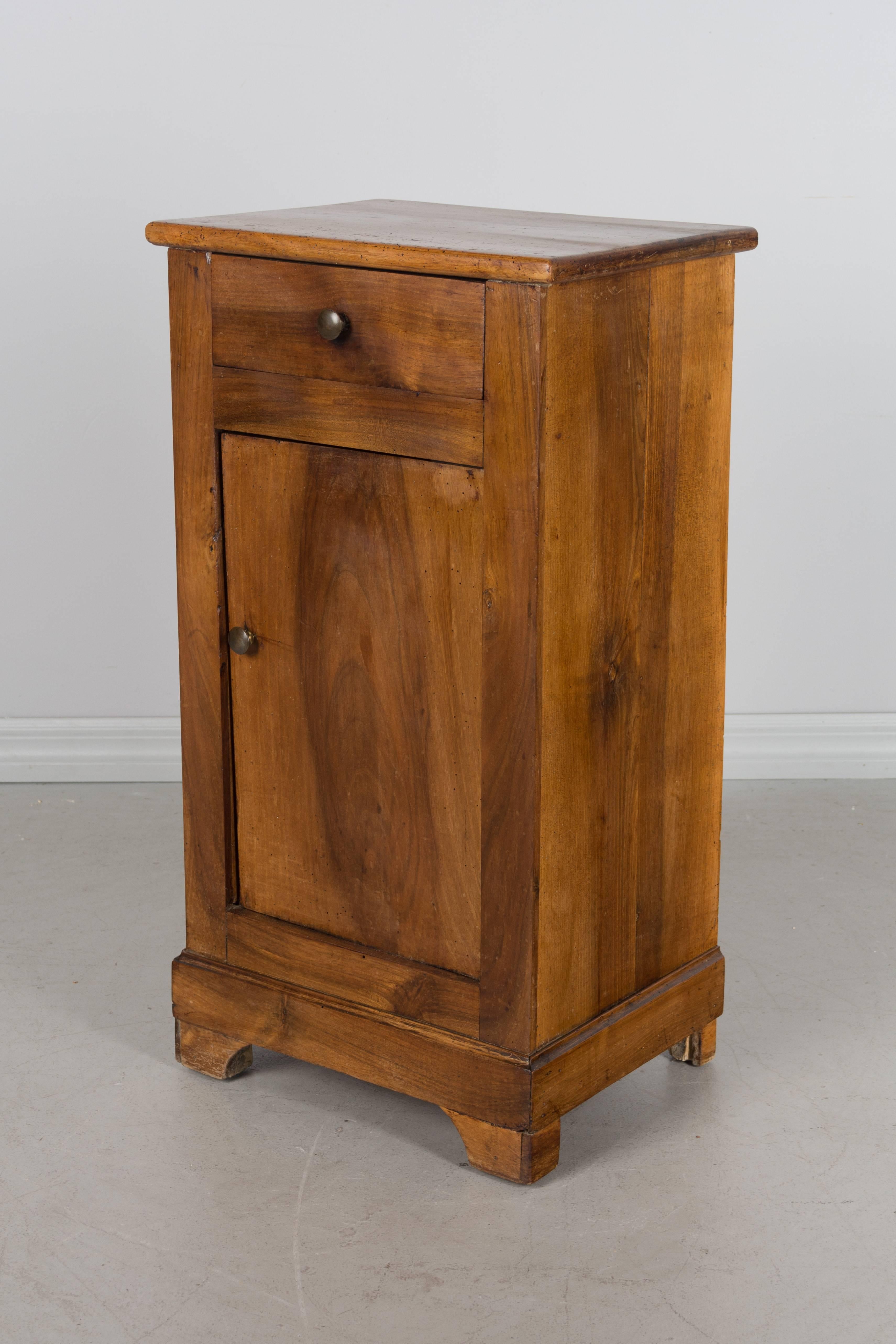 A French Louis Philippe style side table made of solid walnut with one drawer and a door opening to an interior with a single shelf.
More photos available upon request. We have a large selection of French antiques. Please visit our showroom in
