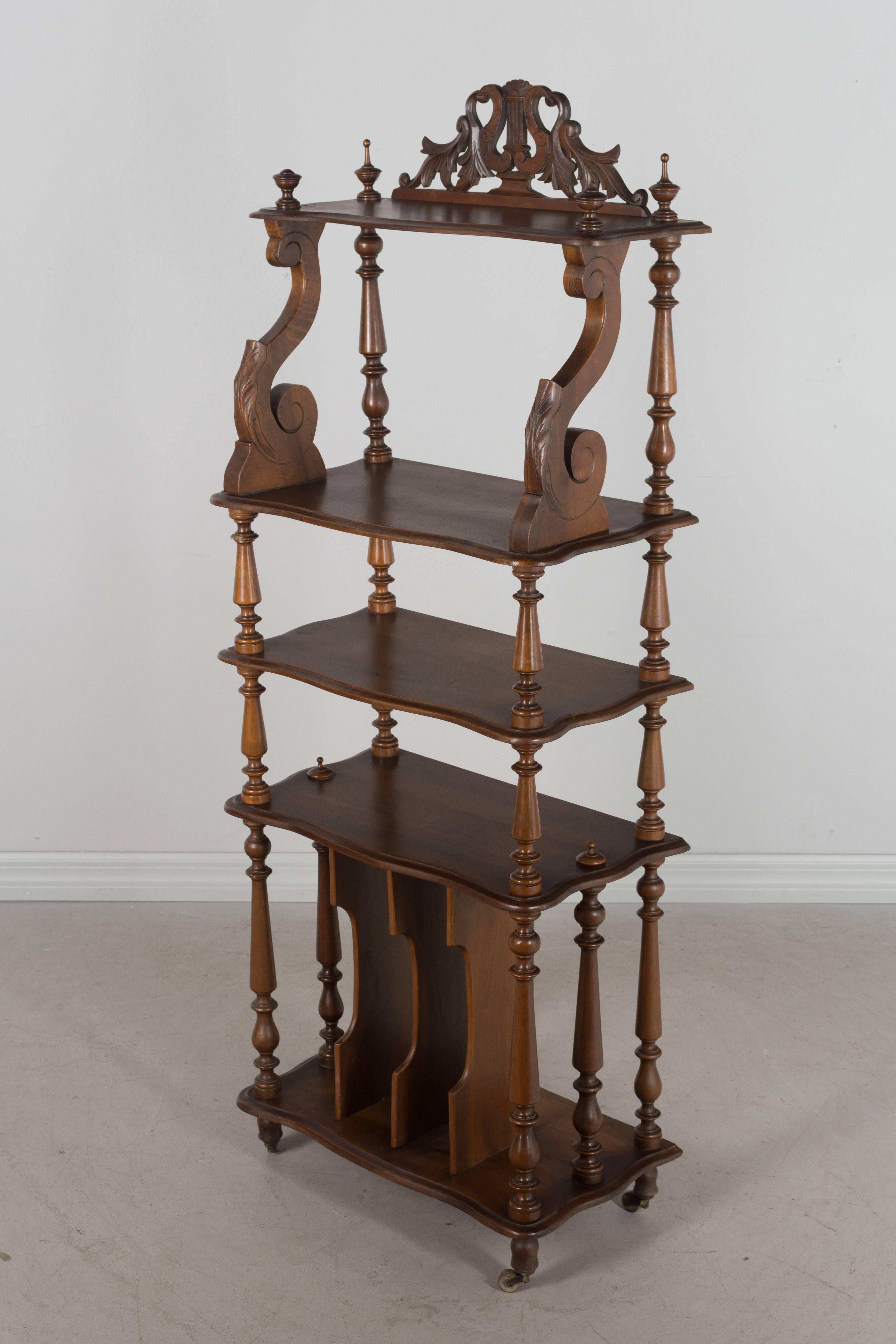 A French music stand or étagère made of walnut with three shelves and vertical dividers at the bottom to store sheet music. Beautiful turned wood spindles and finials. Hand-carved decorative pediment at the top with a lyre and acanthus leaves.
More
