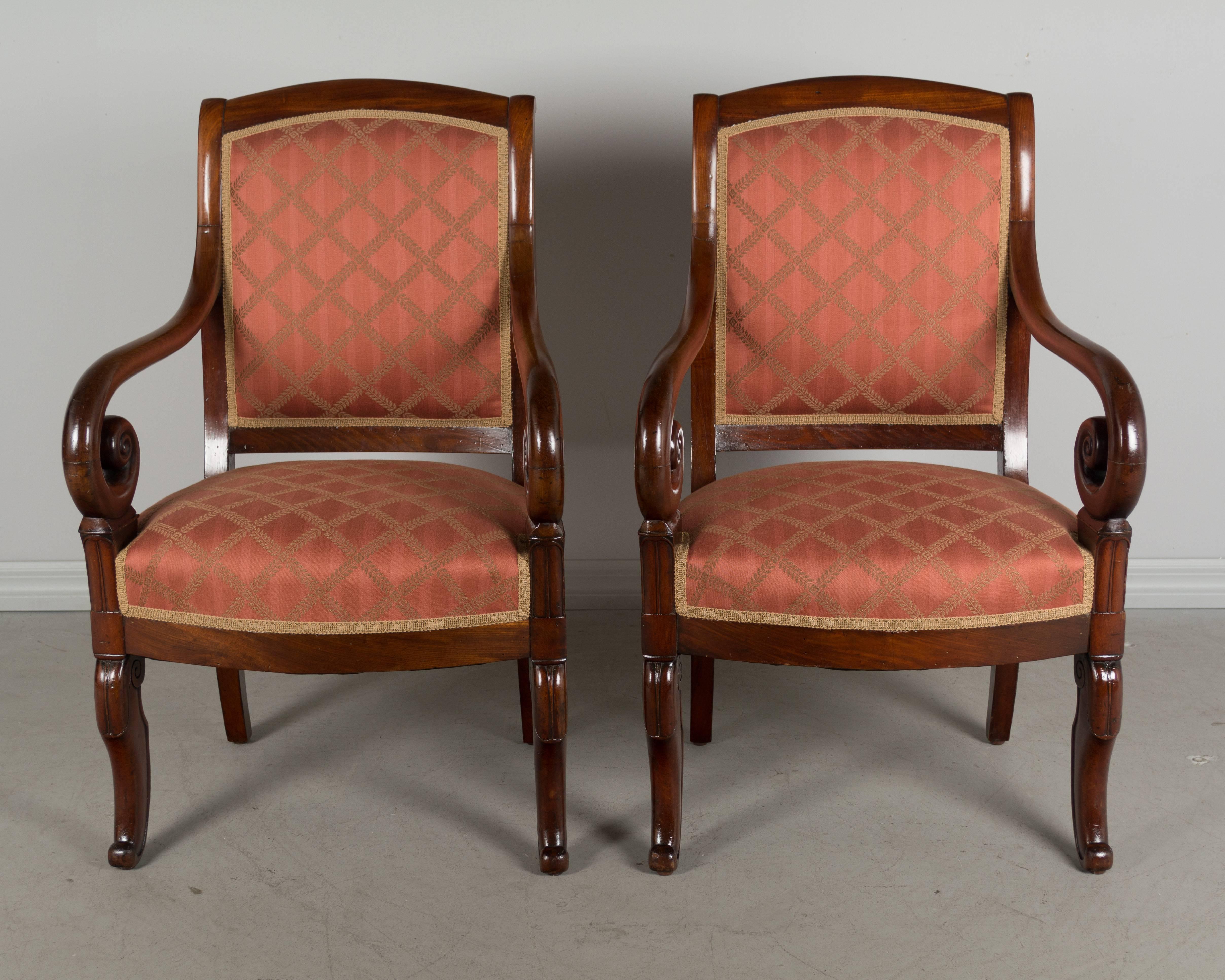 Pair of 19th century French Restauration period armchairs made of solid mahogany with scrolled armrests and subtle carved details on the front legs. French polish finish. Sturdy and comfortable seating. Reupholstered in Beacon Hill fabric.
More