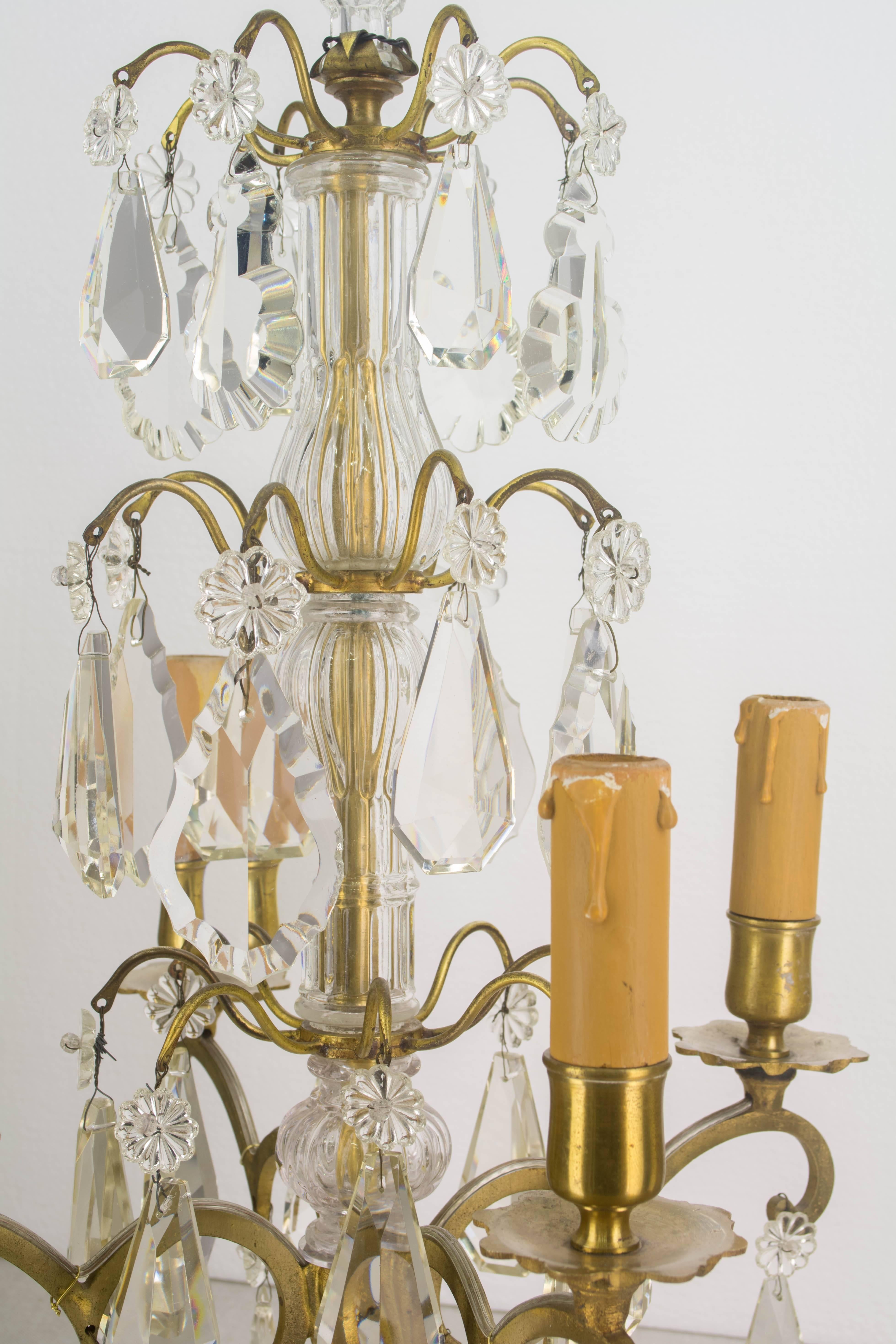 Pair of Louis XV style four-light French girandoles made of brass with three tiers of crystal prisms of various shapes and sizes, crystal columns and finials. Original candle covers. Tall, elegant proportions. Rewired and in working order. European