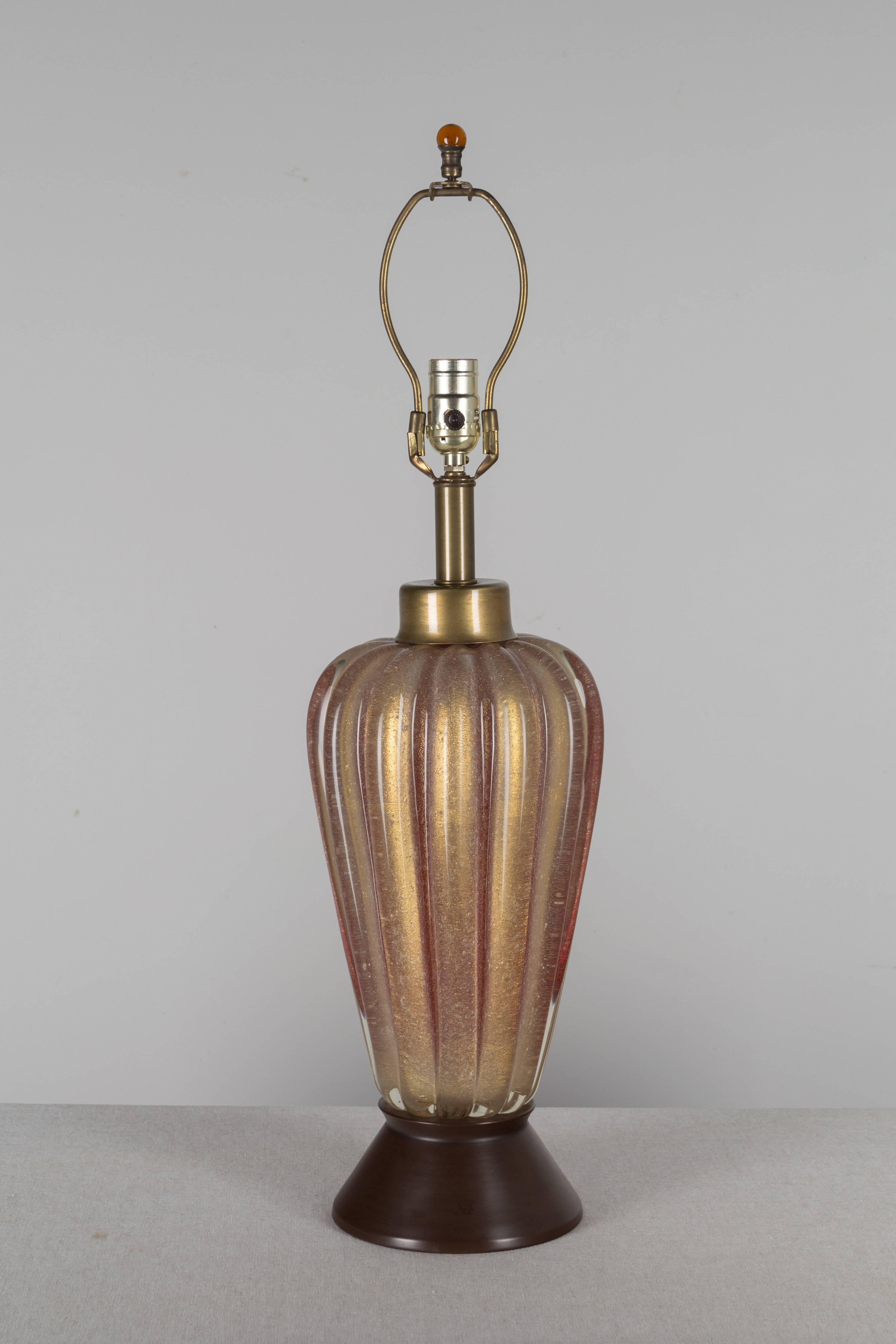 Murano lamp by Seguso, thick ribbed glass, handblown with infused bubbles. Red with heavy gold inclusions give the glass a warm amber color. Metal base. Rare, beautiful color. Silk shade is not included but measures 10.5