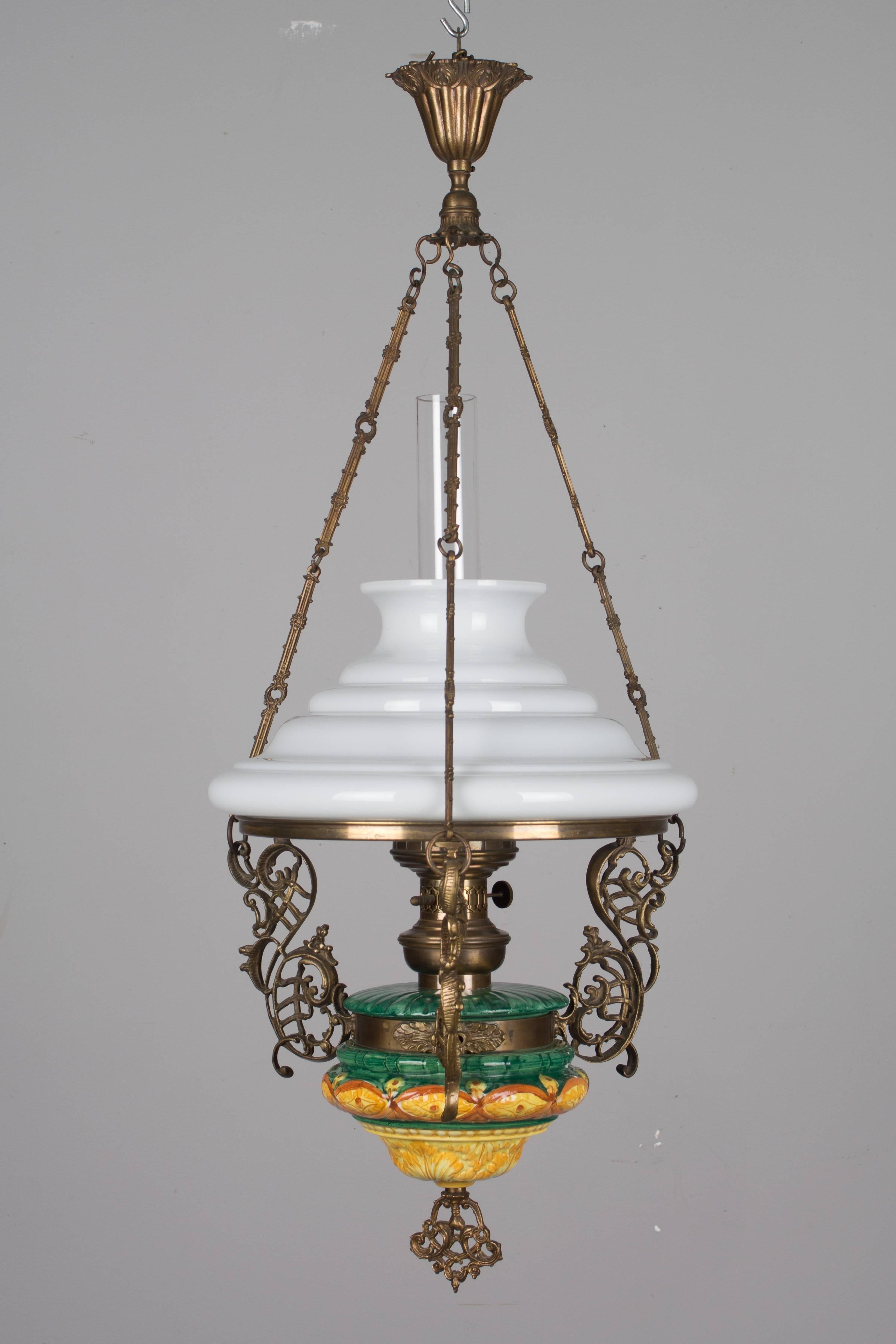 A charming 19th century Country French hanging oil lamp. Bronze and ceramic with glass shade and chimney. May be wired and converted to electric. Measures: 35" height (to top of canopy) x 15" diameter. In excellent condition with only a