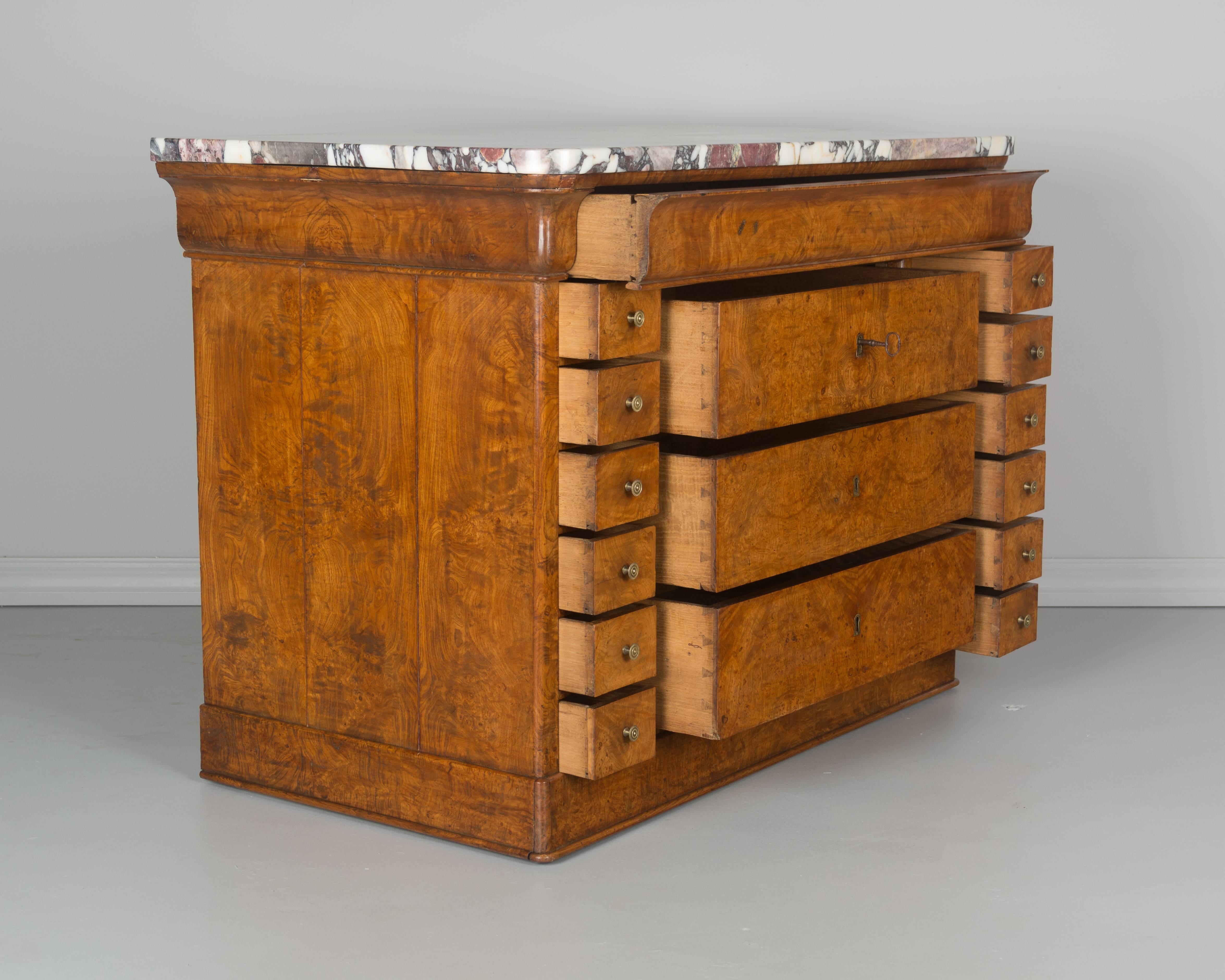 An early 19th century French Charles X commode made of veneer of bird's eye maple over solid oak as a secondary wood. A very unusual chest with two rows of six small drawers flanking three drawers with locks and one shallow "hidden"
