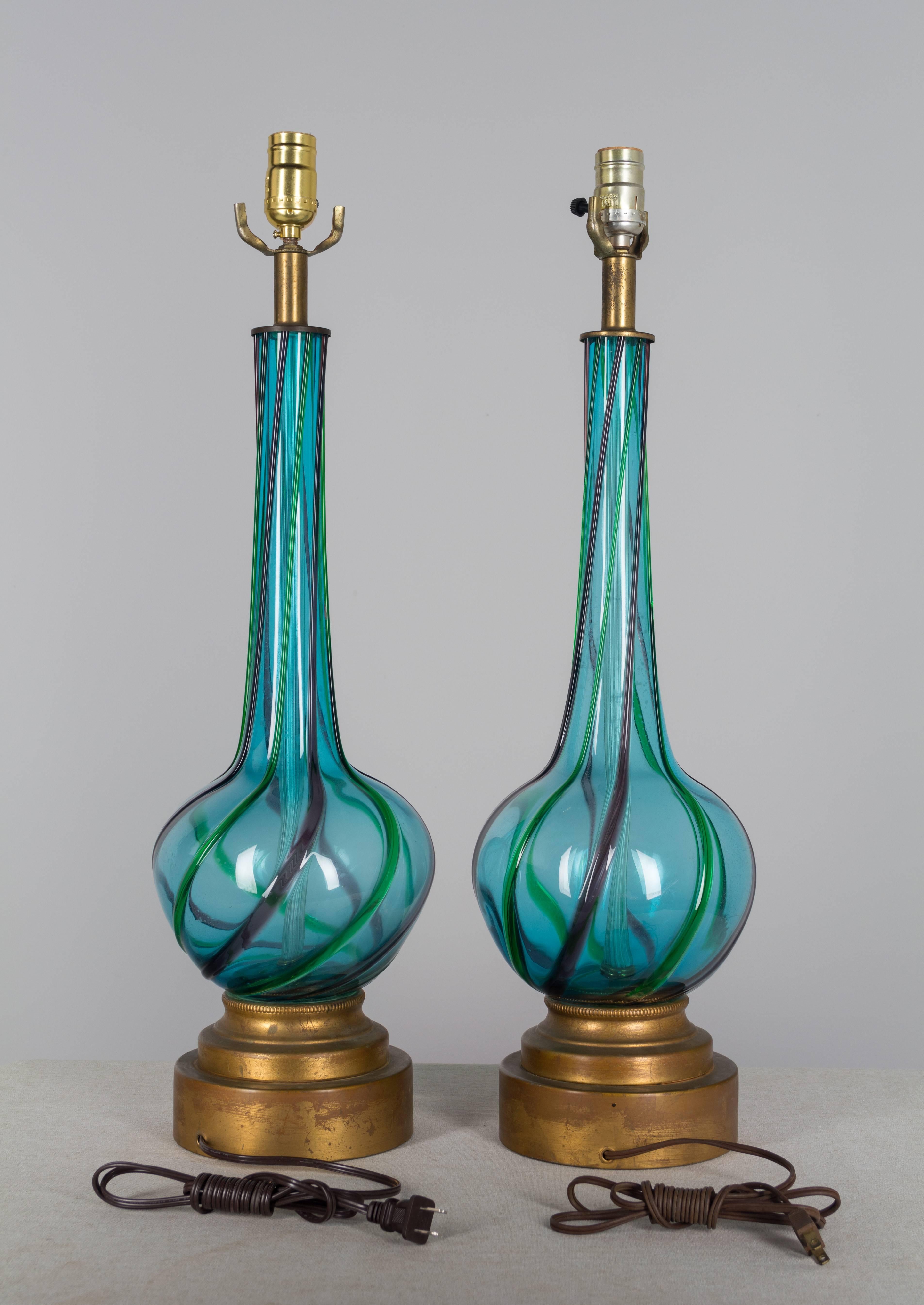 Pair of Mid-Century Murano glass lamps. Handblown, clear aqua blue color with swirling stripes of green and purple. Base is metal with gold patina. All original. The glass is in excellent condition, but has not been cleaned on the inside. These