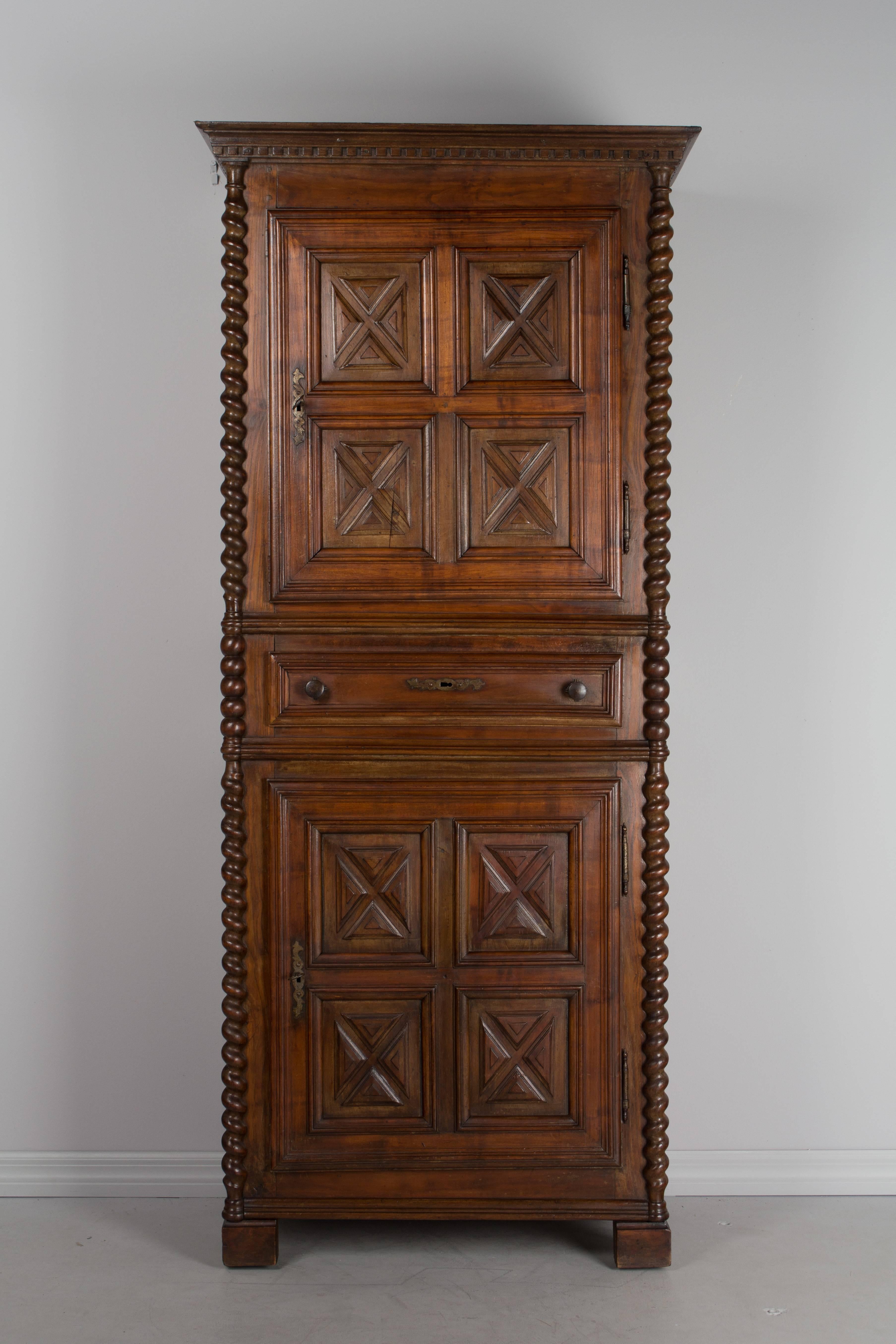 19th century Louis XIV style Homme debout, or tall narrow armoire, made of solid walnut with raised panels and turned twisted columns. Two doors open to interior shelves. One dovetailed drawer. Original hardware with working locks and two keys.