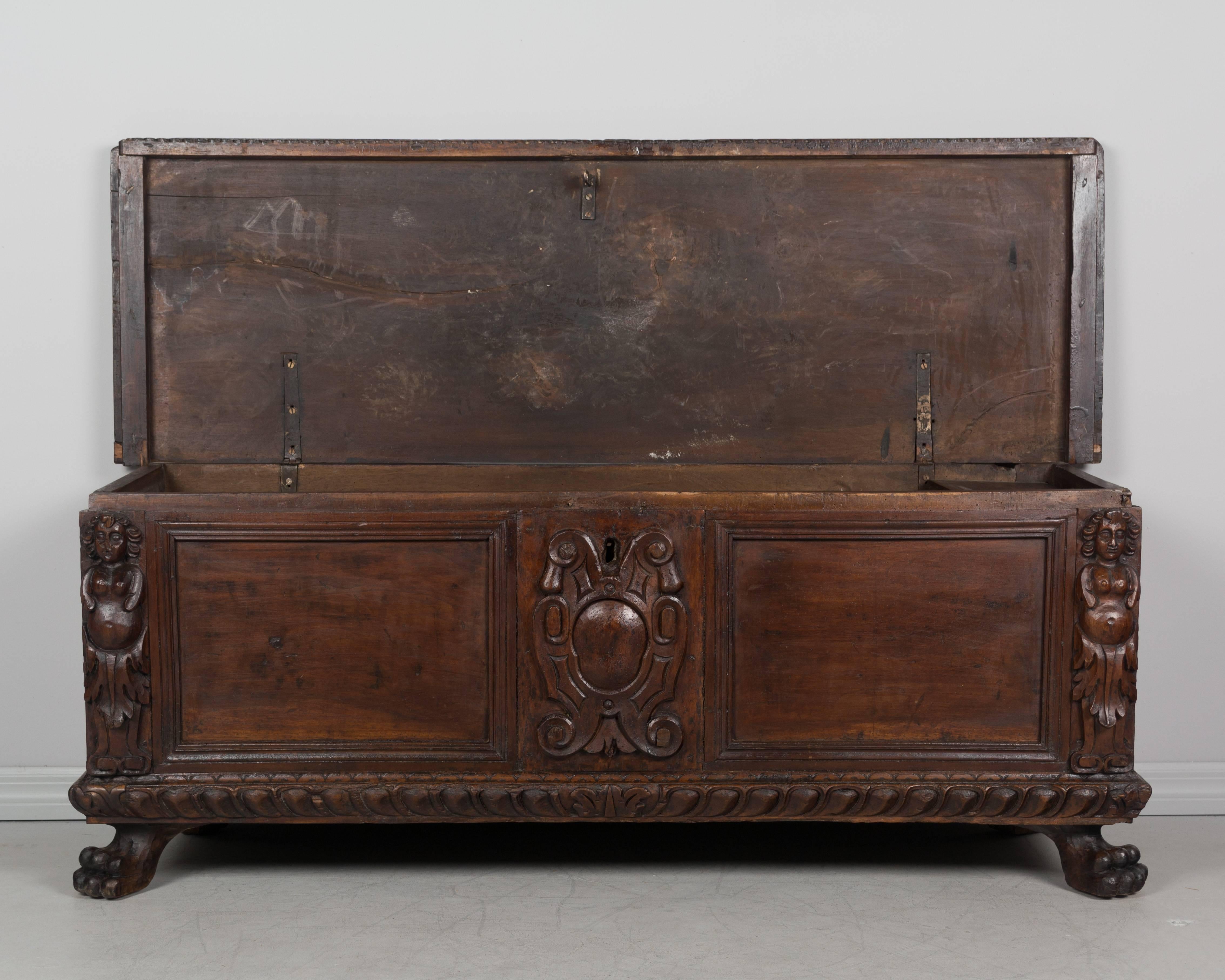 A fine 18th century Italian cassone, or large blanket chest, made of solid walnut. Bold details are hand carved in high relief and include a central crest, a pair of caryatids on the corners, dentil decoration along the top and bottom and large lion