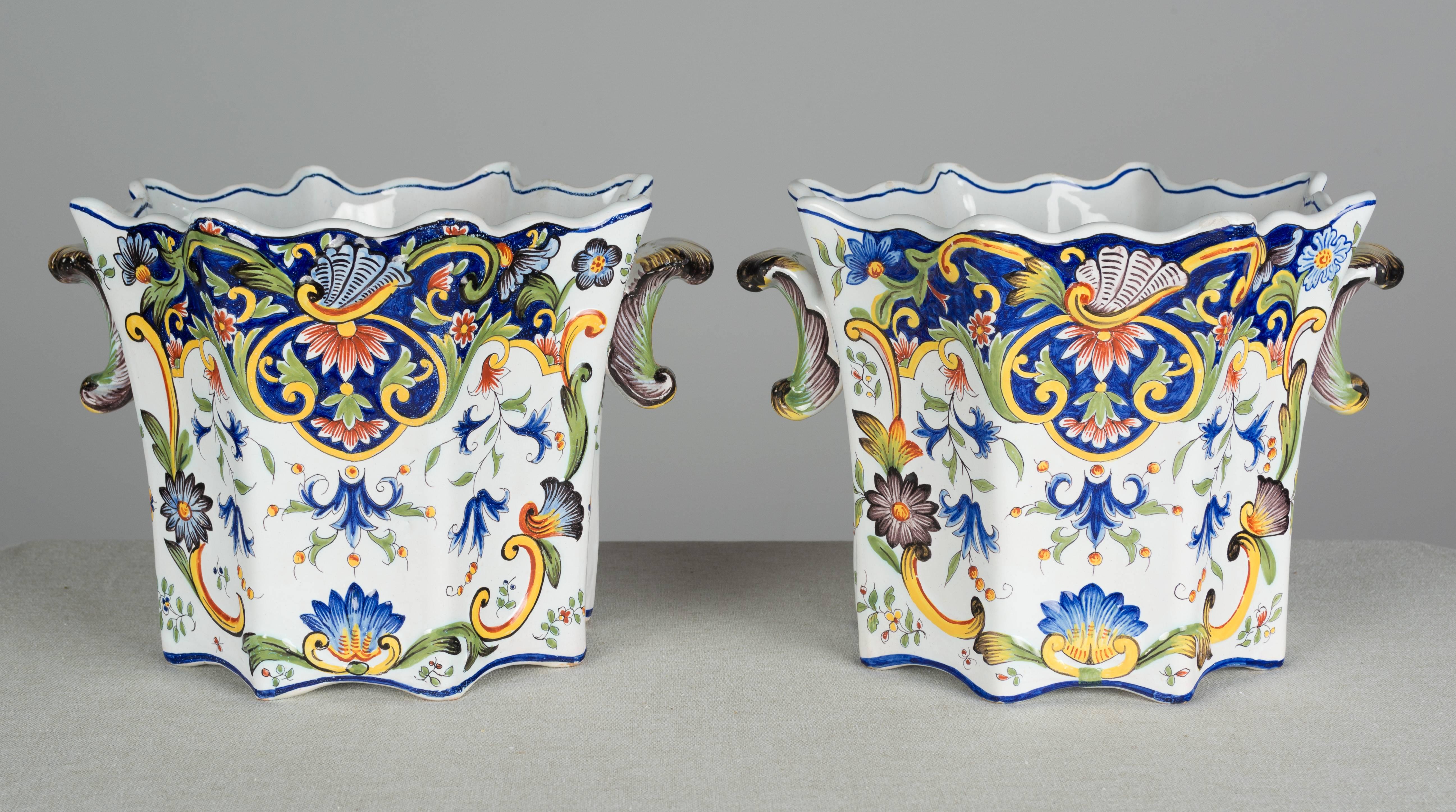 Pair of 19th century. French faience Fourmaintraux Desvres cache pots, or planters. Hand-painted in typical floral design with beautiful vivid colors of blue green and yellow on white ground. Fluted shape with scalloped edges and small handles. The