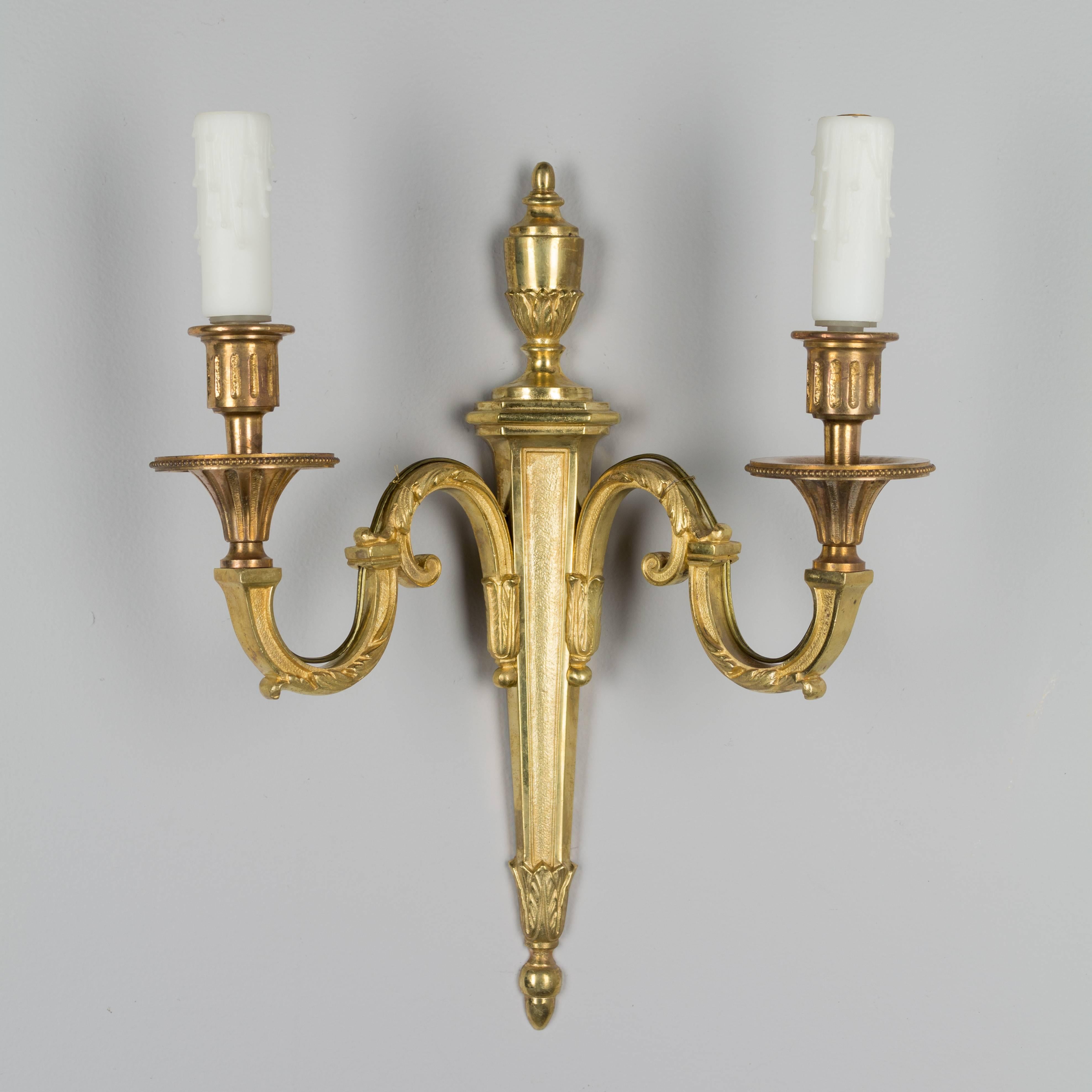 Pair of Louis XVI style two-light bronze sconces with  gold patina. Rewired with European sockets. New resin candle covers. Two pairs available. $650/pair.
More photos available upon request. We have a large selection of French antiques. Please