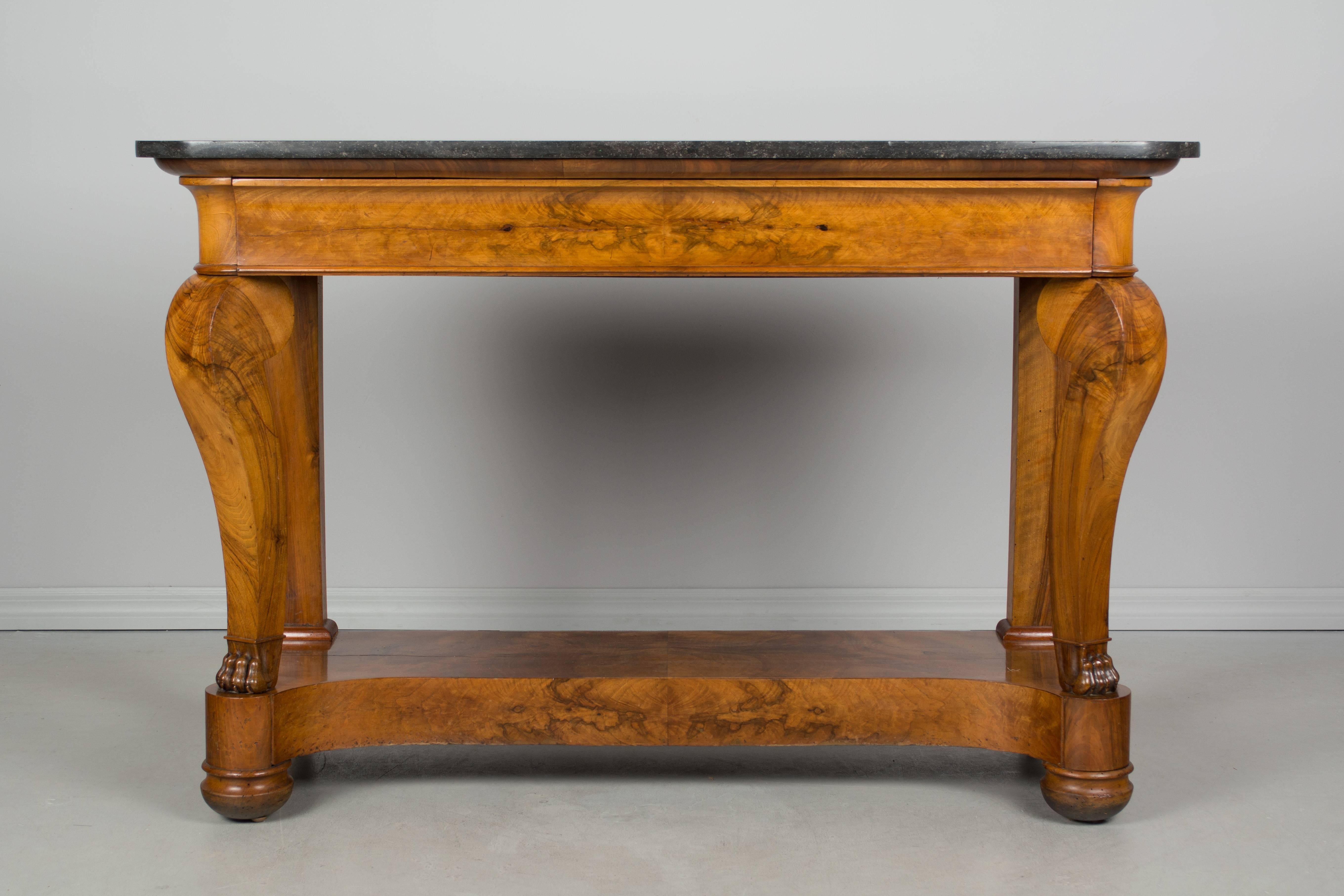 19th century French Restauration period console made of solid walnut with bookmatched veneer of walnut on the lower shelf and drawer face. Beautiful wood grain on the sculptural, shaped front legs ending in carved lion paws. Dovetailed construction