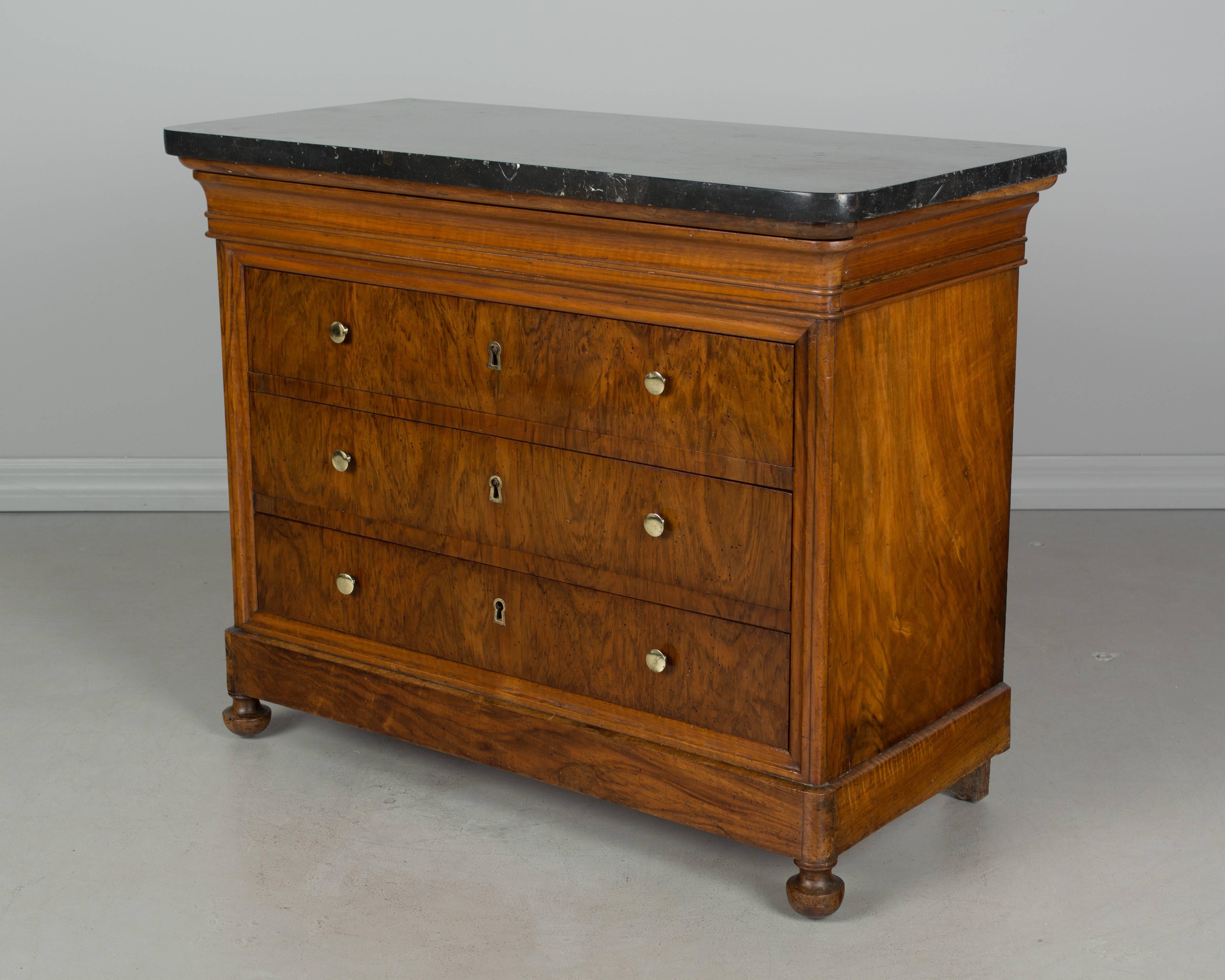 A small 19th century, French, Louis Philippe child's size commode with three dovetailed drawers and a hidden top drawer. Made of solid walnut with beautiful veneer of walnut on the face of the drawers. Pine as a secondary wood. Original brass knobs.