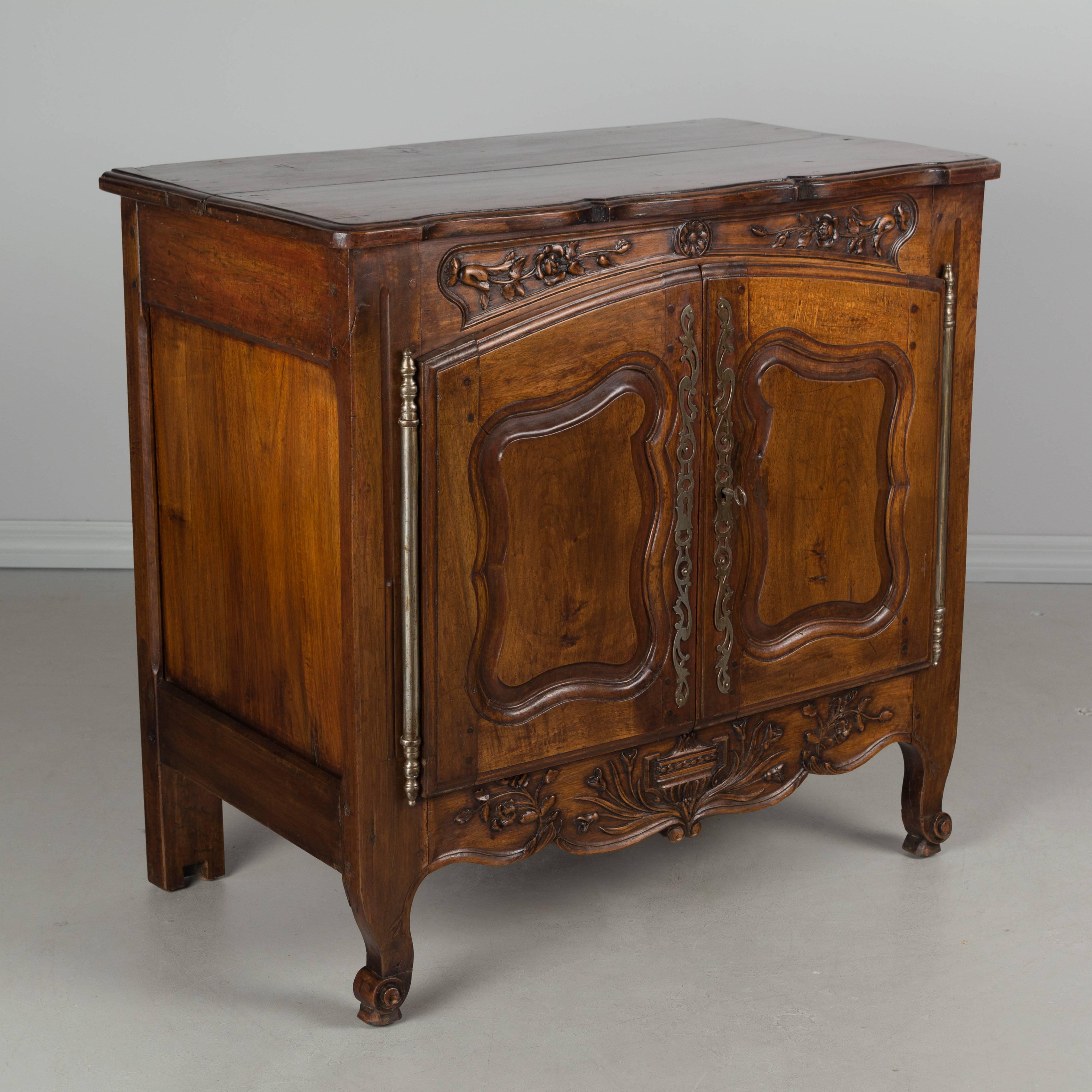 A Country French, Louis XV style buffet from Provence. Made of solid walnut with nice hand-carved decoration especially on the apron. Beautiful wood with waxed finish. Opens to one interior shelf. Carved snail toes in the front. The back legs have