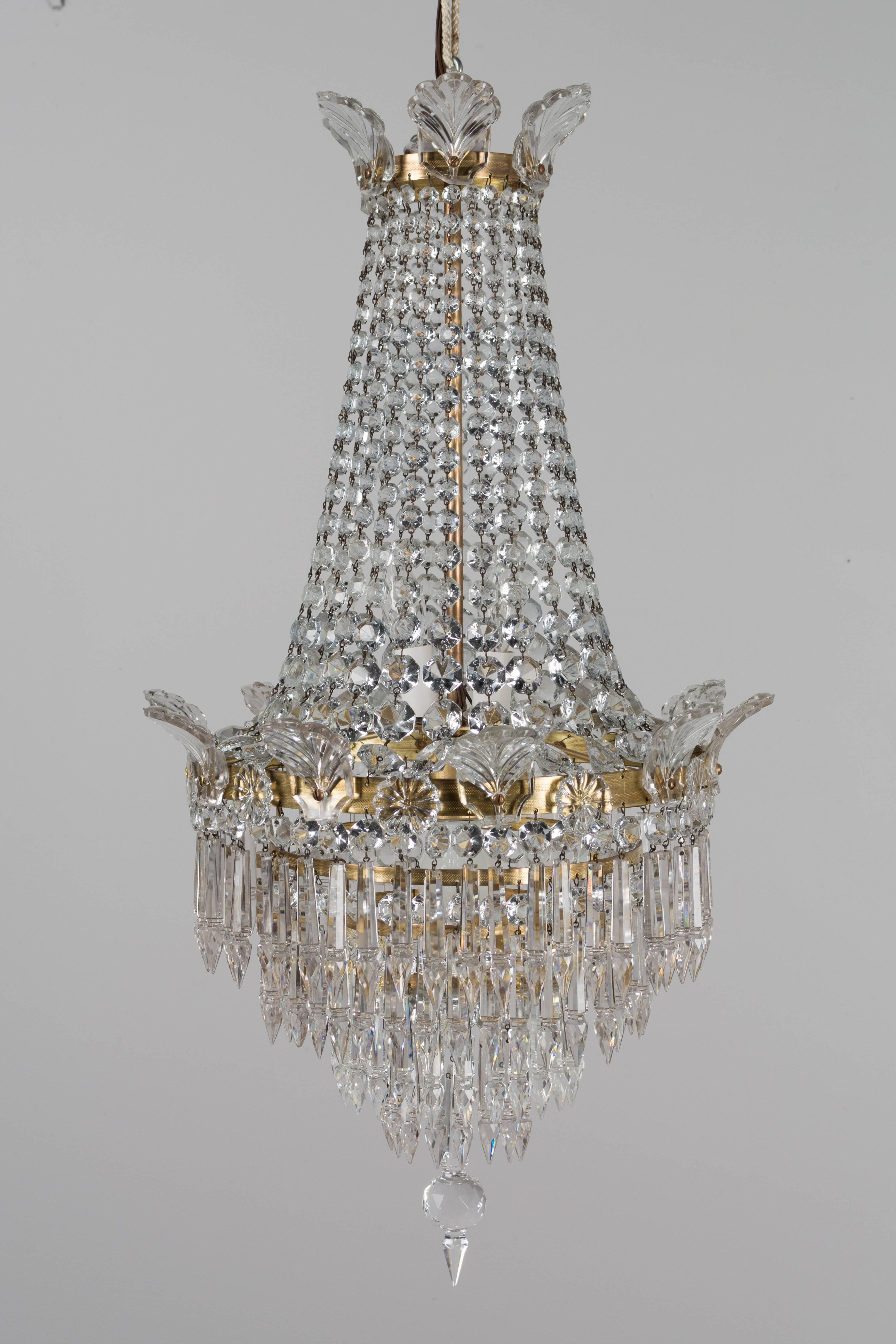 A French Empire style three-light crystal chandelier with brass frame. A beautiful waterfall form with multiple strands of faceted bead chains and four tiers of hanging prisms. The faceted sphere at the bottom is new, but matches the original. One