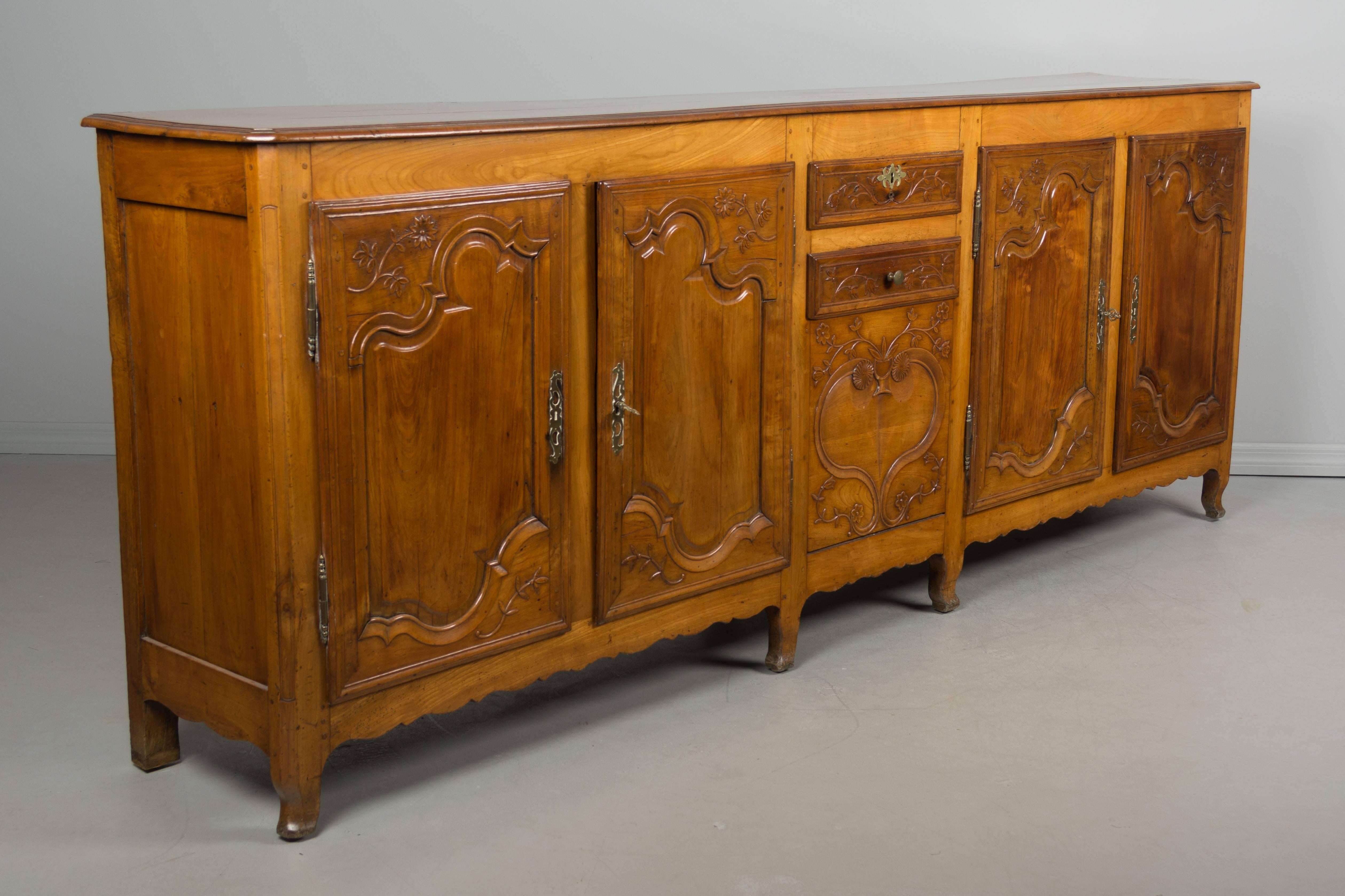 A large 19th century Louis XV enfilade, or sideboard, from Picardie in the North of France. Made of solid cherrywood with fine hand carvings. Ample storage, with doors on the left opening to two interior shelves and the doors on the right opening to