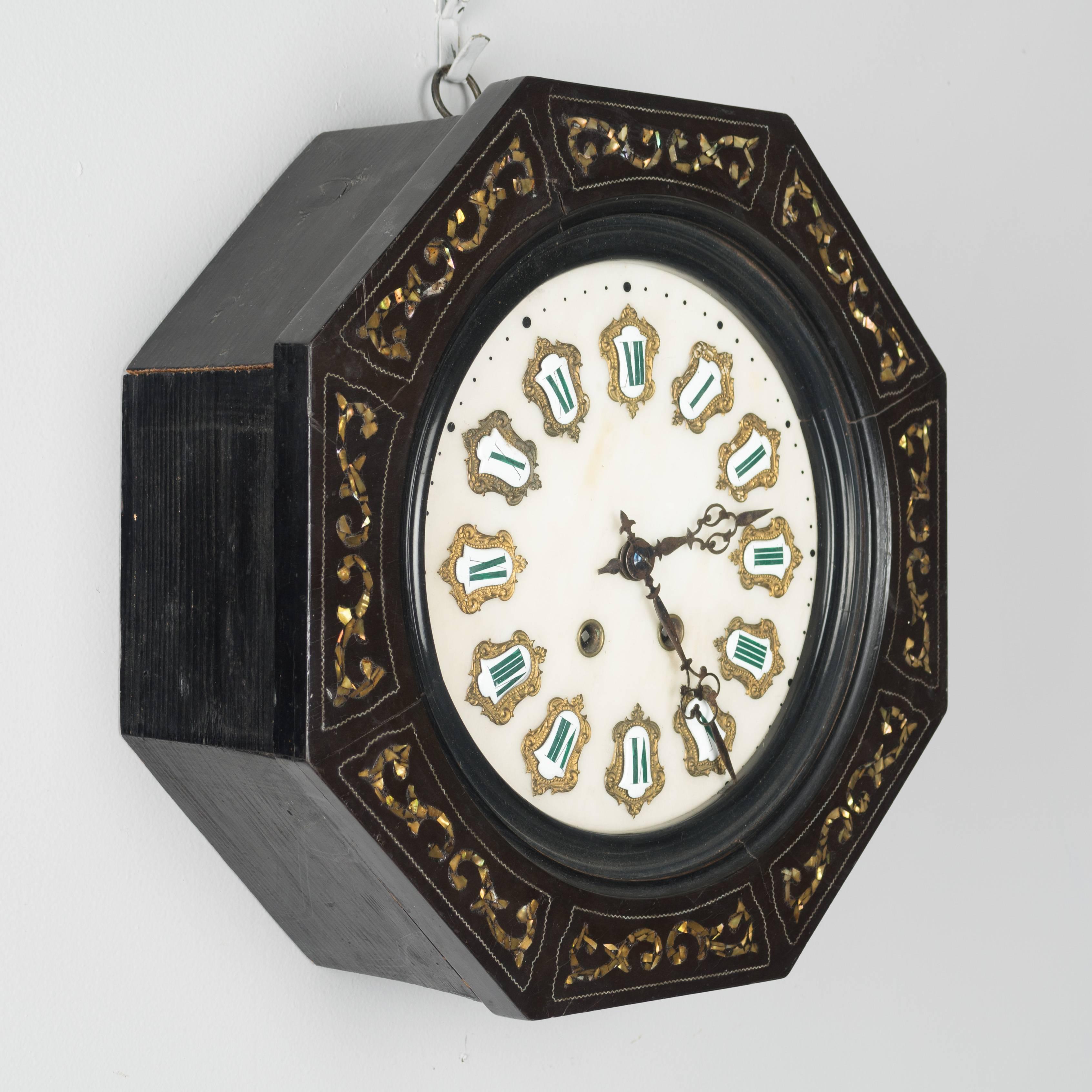 A 19th century French Napoleon III wall clock. Octagonal ebonized wood frame with mother-of-pearl inlay decoration. Marble face inlaid with ceramic roman numerals surrounded by brass decoration. Movement has been cleaned and is in working