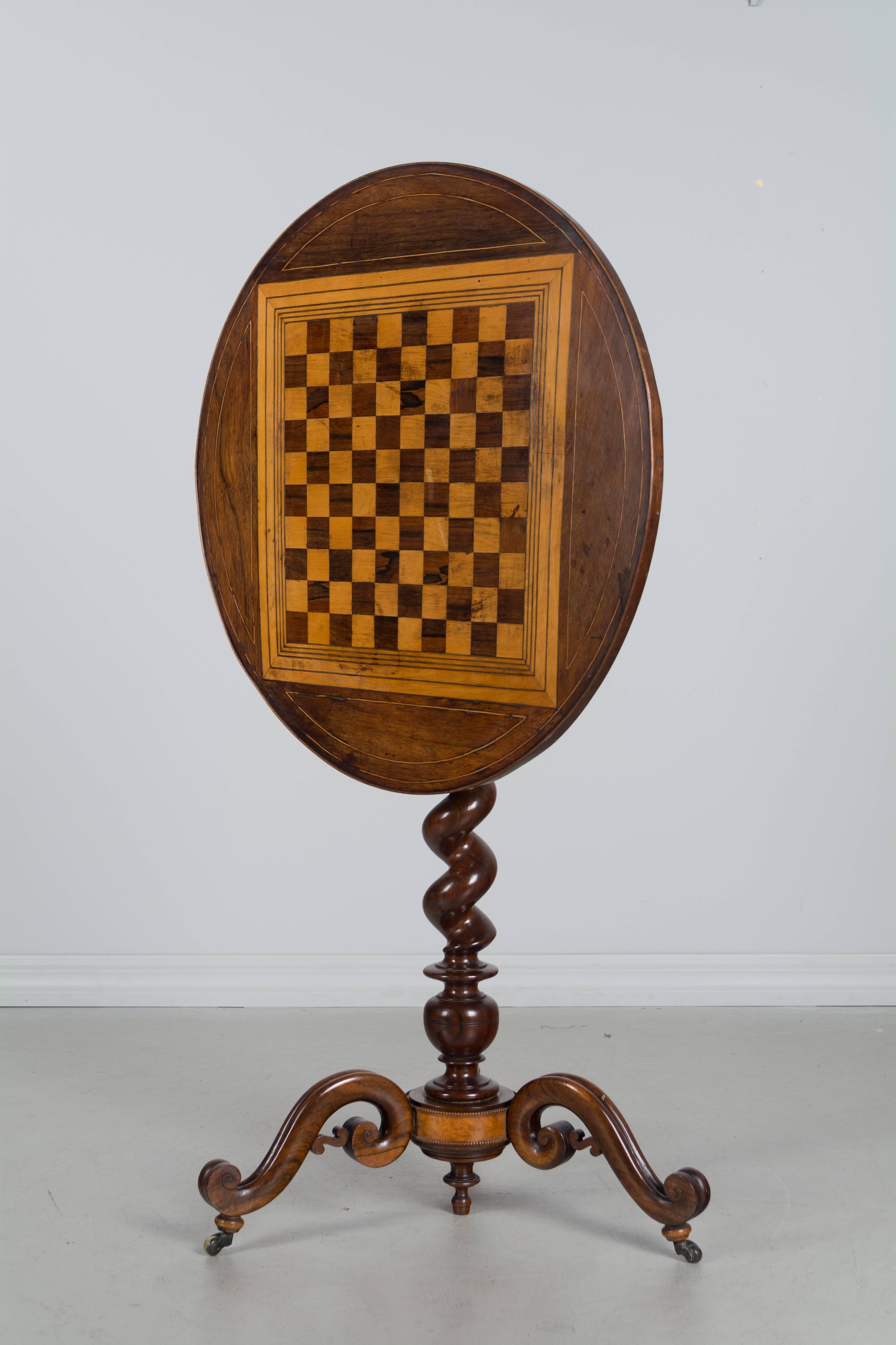 An early 19th century French tilt-top game table with finely turned pedestal base made of solid rosewood. A beautifully crafted table with precise inlaid checkerboard and beautifully carved legs. The top shows nicely when tilted, but is quite