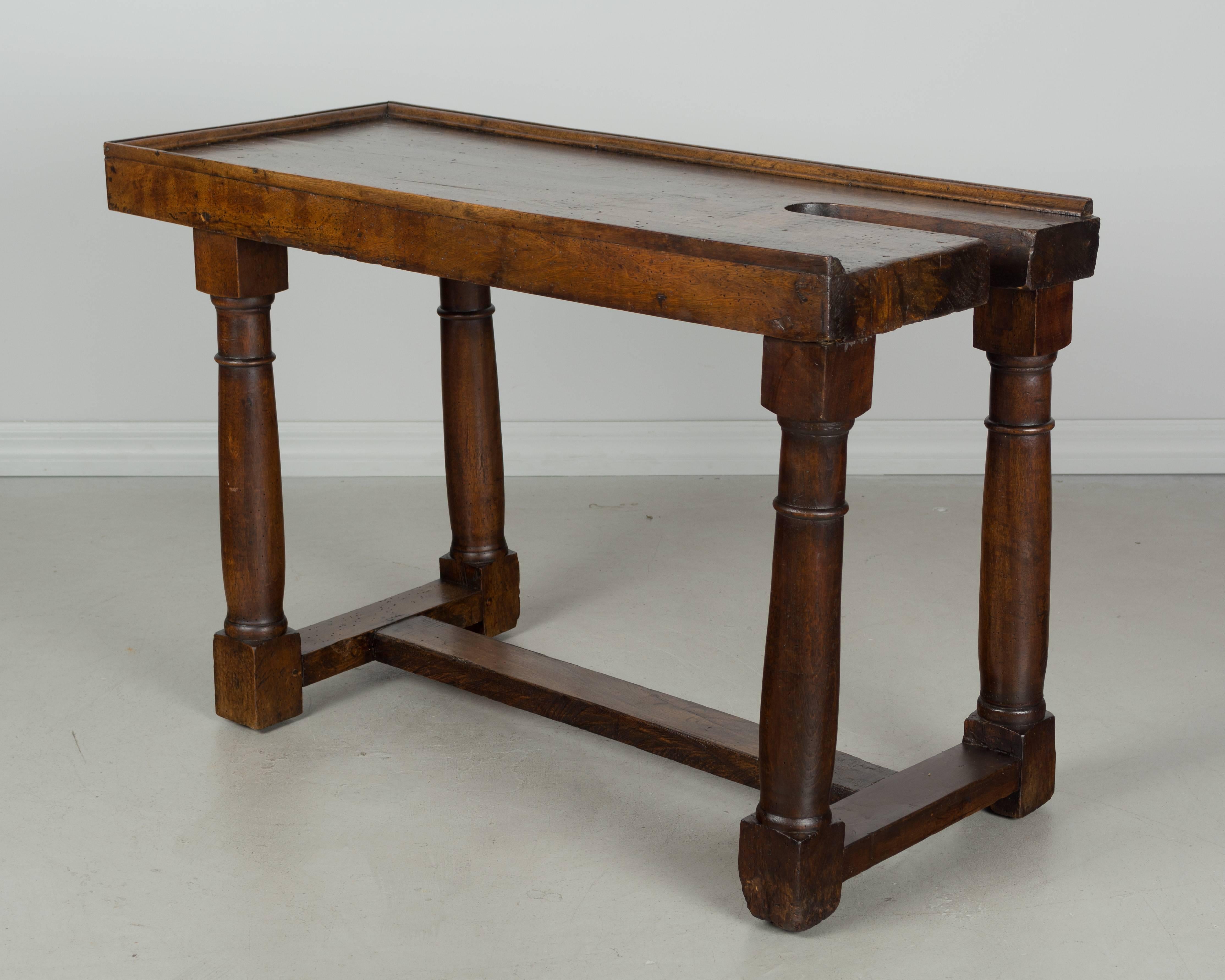 An early 19th century French rustic work table made with a 2-1/2 inch thick solid walnut top. Sturdy base with turned legs and stretcher. Beautiful old patina with waxed finish. 
More photos available upon request. We have a large selection of