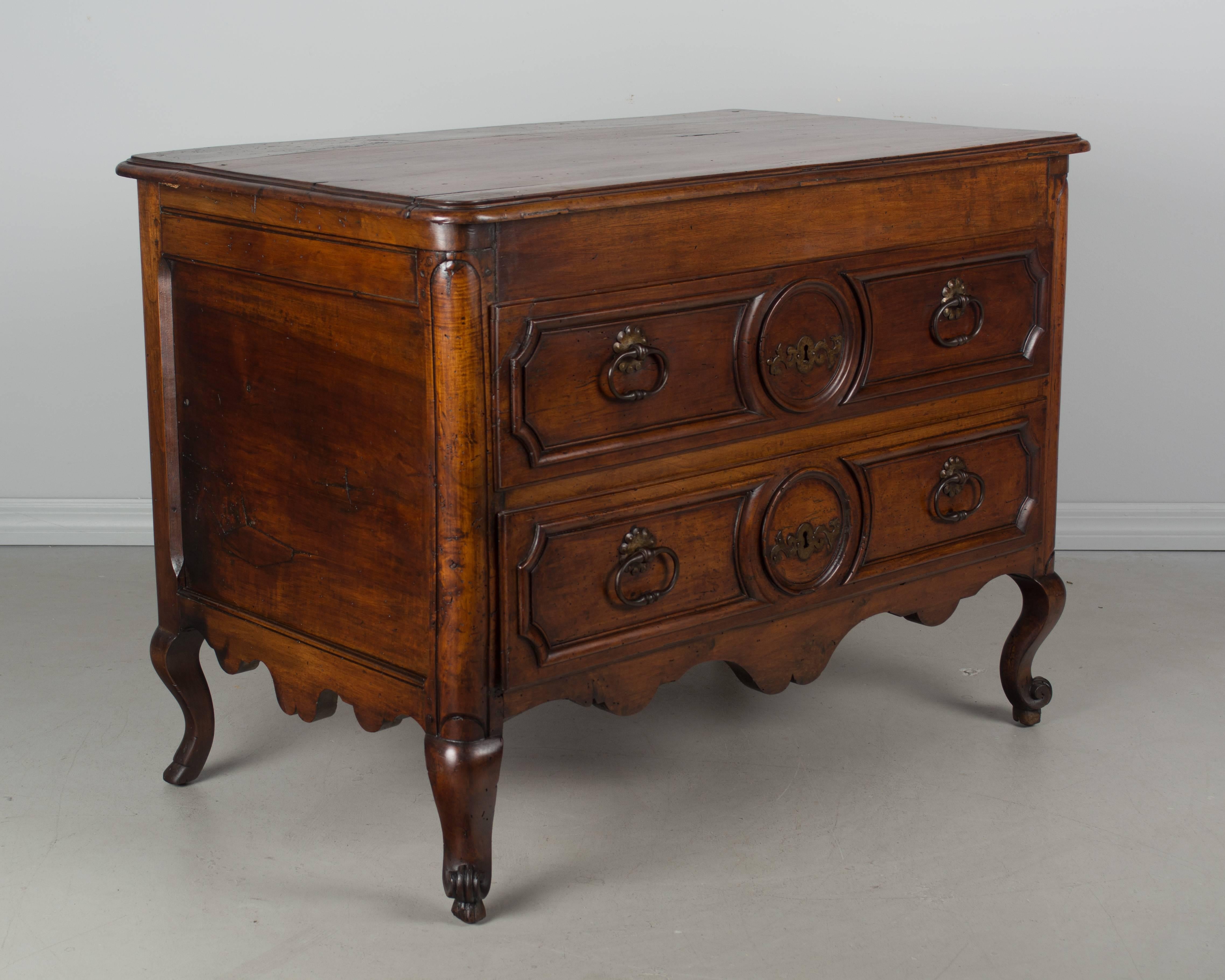 A Louis XV style French commode, or chest of drawers, made of solid hand-carved walnut and finished on all four sides. Beautiful quality to the wood with a waxed patina. This chest was converted from a blanket chest in the 19th century. Two