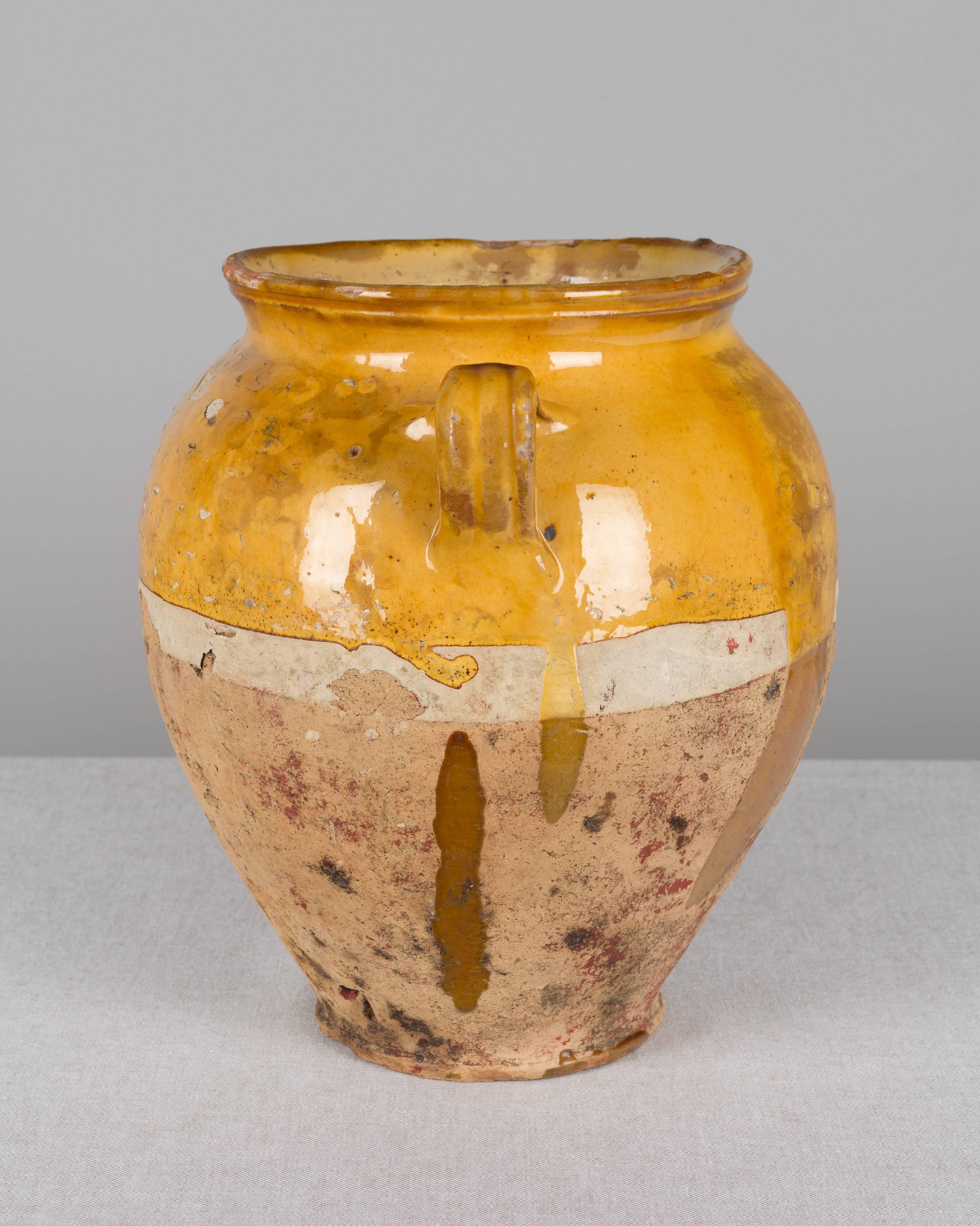 An earthenware confit pot from the Southwest of France with traditional ochre yellow glaze on the top half and nice old patina with bits of red on the lower half. In excellent condition with very little wear. There is a hole in the bottom, perfect