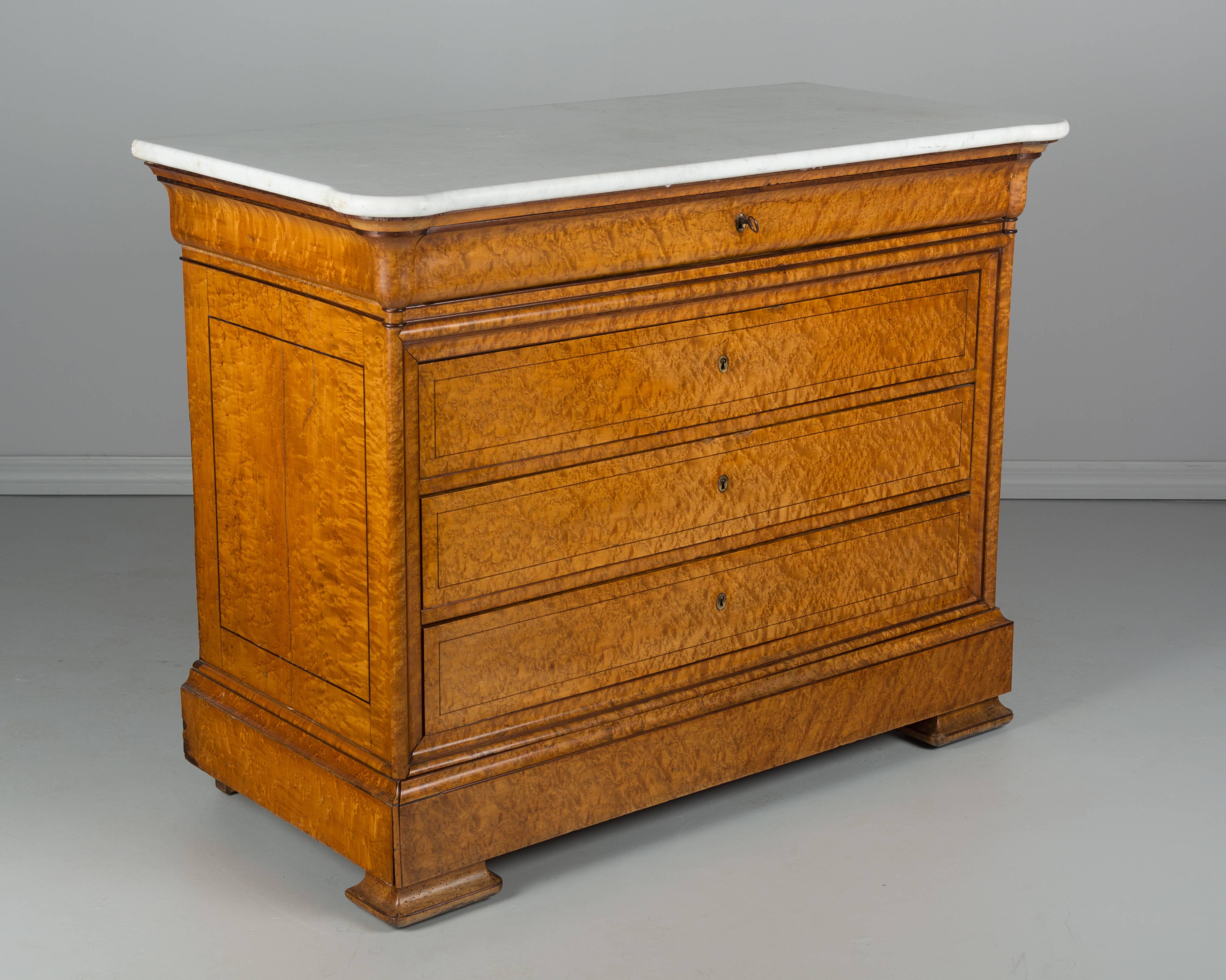 An early 19th century French Charles X commode, or chest of drawers, made of veneer of bird's-eye maple over solid oak with mahogany trim. Five dovetailed drawers provide ample storage with working locks and one key. Two brass escutcheons are