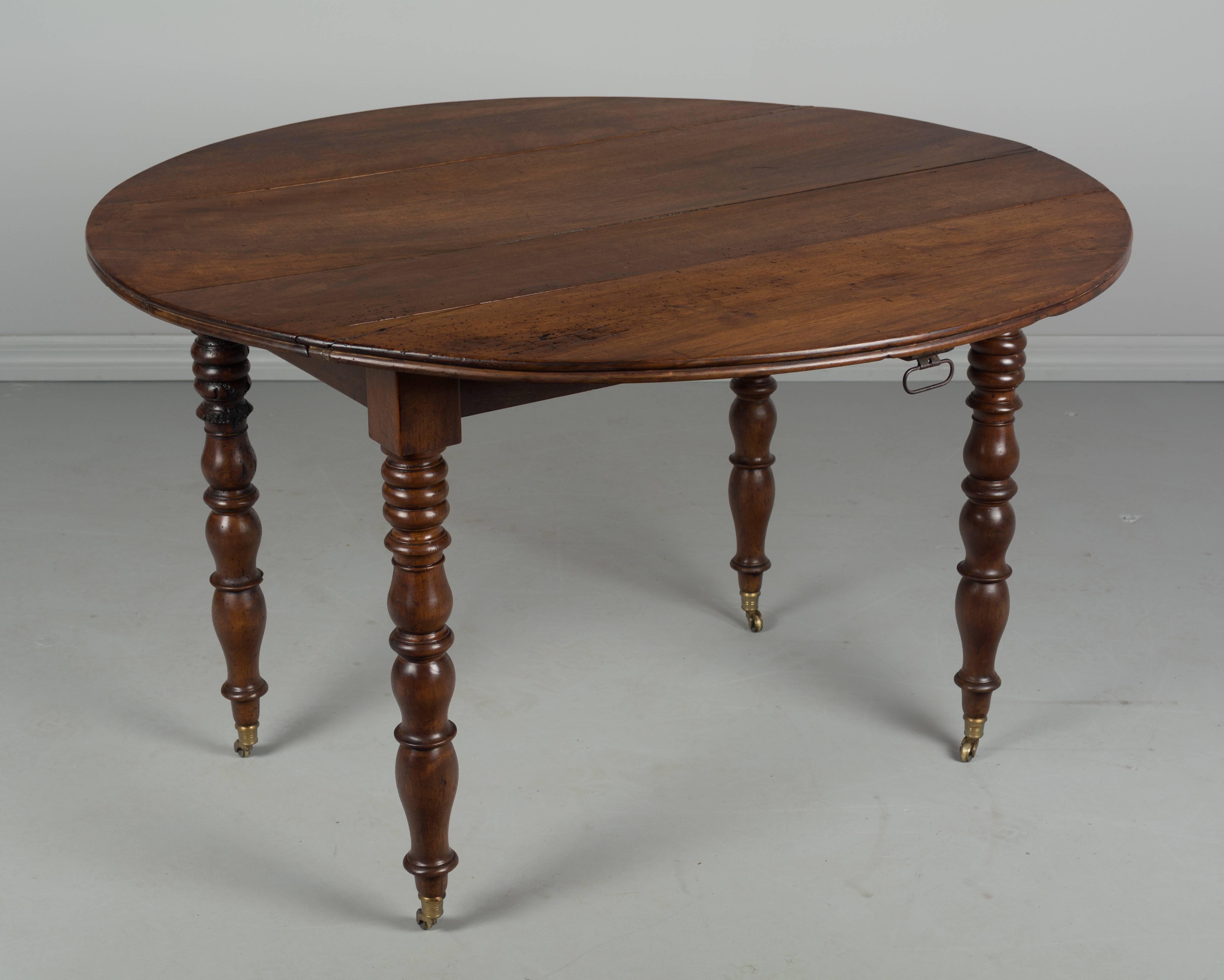 A 19th century French Louis Philippe drop-leaf table made of solid walnut. Turned legs with new brass wheels. Excellent quality. Beautiful wood grain with waxed finish. When closed the table is 22.5