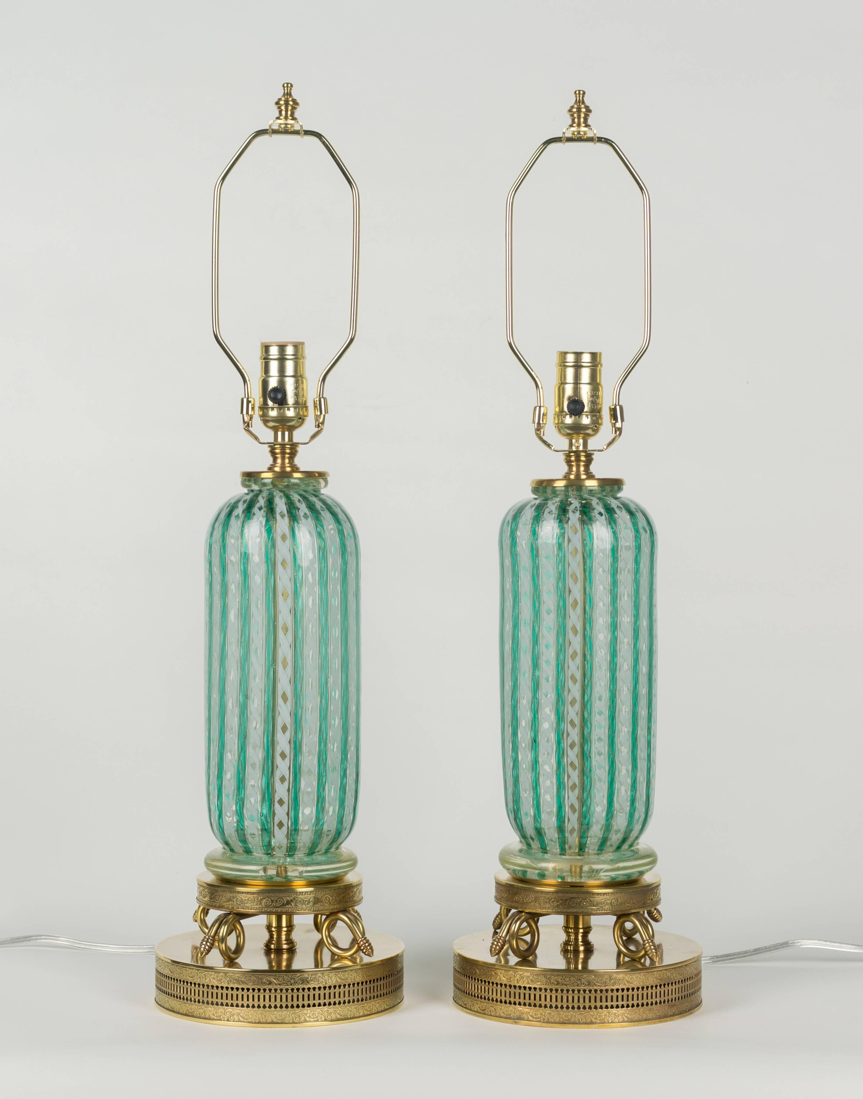 Pair of exquisite Murano glass lamps. Latticino ribbons of green with Zanfirico white stripes. Gold inclusions throughout. Original polished brass fittings, including an ornate tiered base with delicate embossed floral detail and serpentine loops.