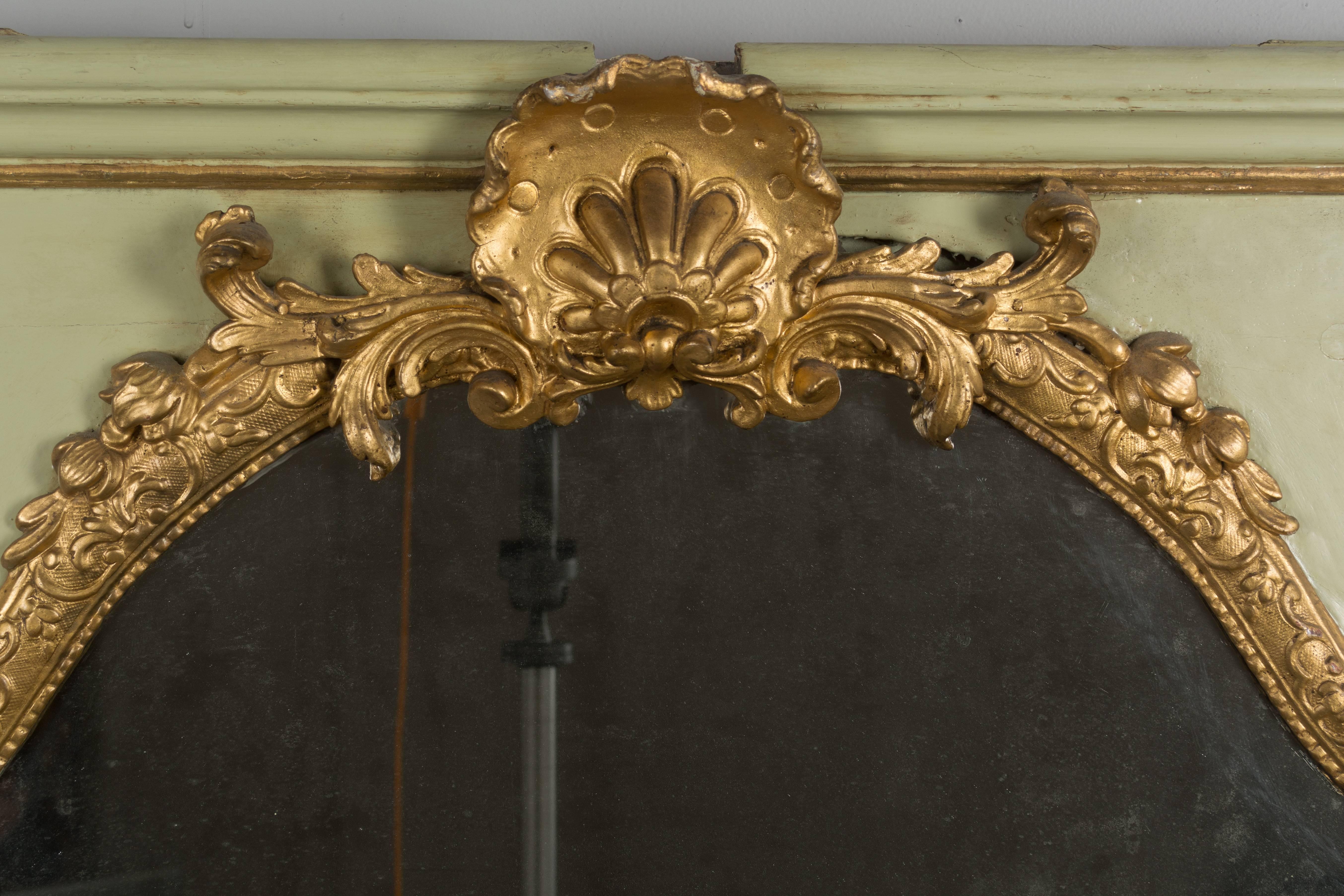 An 18th century Louis XVI French trumeau that was part of a boiseries, or wall paneling. Original mirror in three parts with old silvering. Parcel-gilt frame made of pine with pale green painted surface and gilded carved decoration. Resurfaced paint
