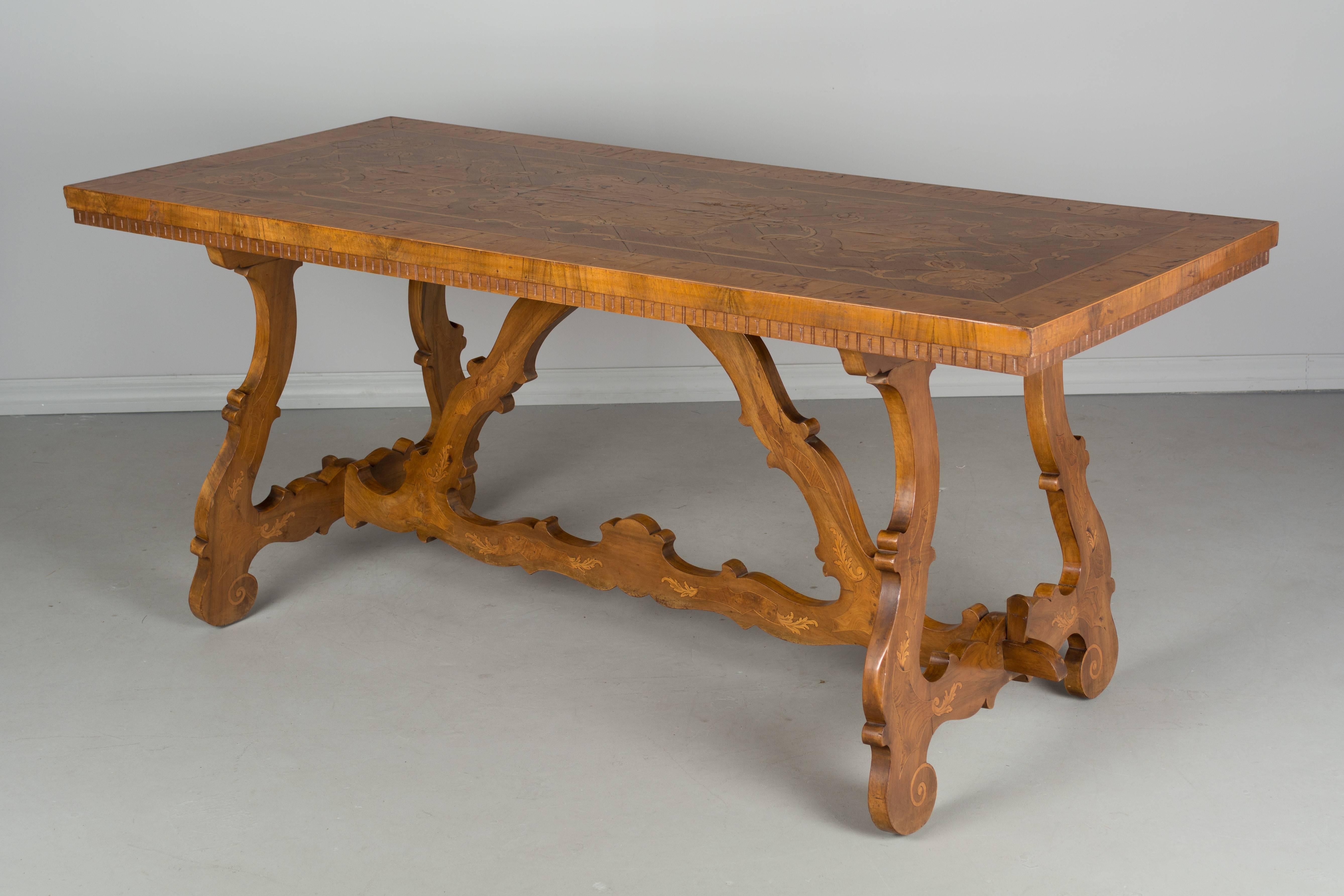 A French marquetry center table made of solid walnut with burl of elm inlay. Sculptural Spanish Baroque style trestle type base with lyre shaped legs and stretcher. The rectangular top has beautiful inlaid decoration with bookmatched veneer and