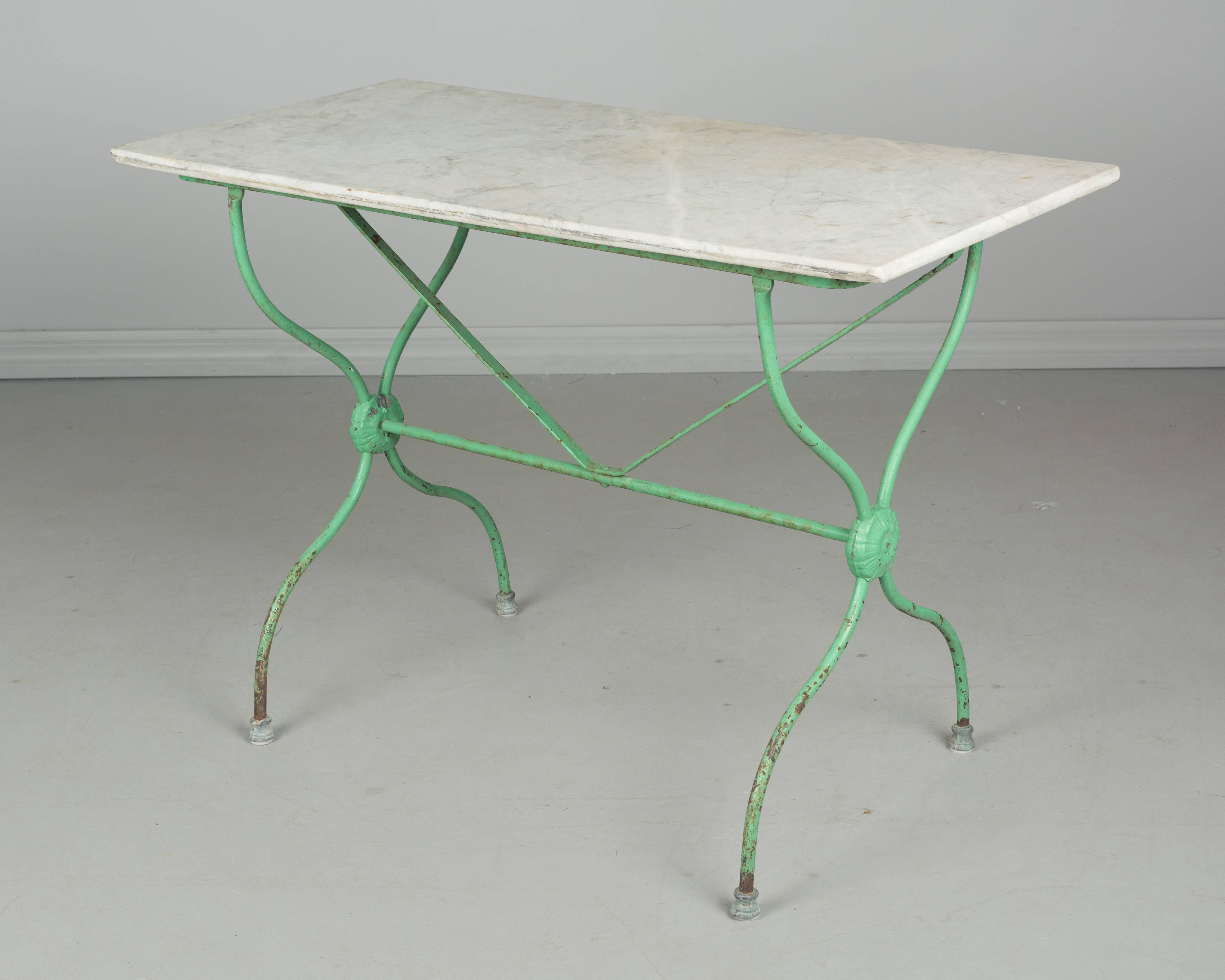 A 19th century French cast iron bistro table with green painted patina and marble top. All original. More photos available upon request. We have a large selection of French antiques at Olivier Fleury, Inc. Please visit our showroom in Winter Park,