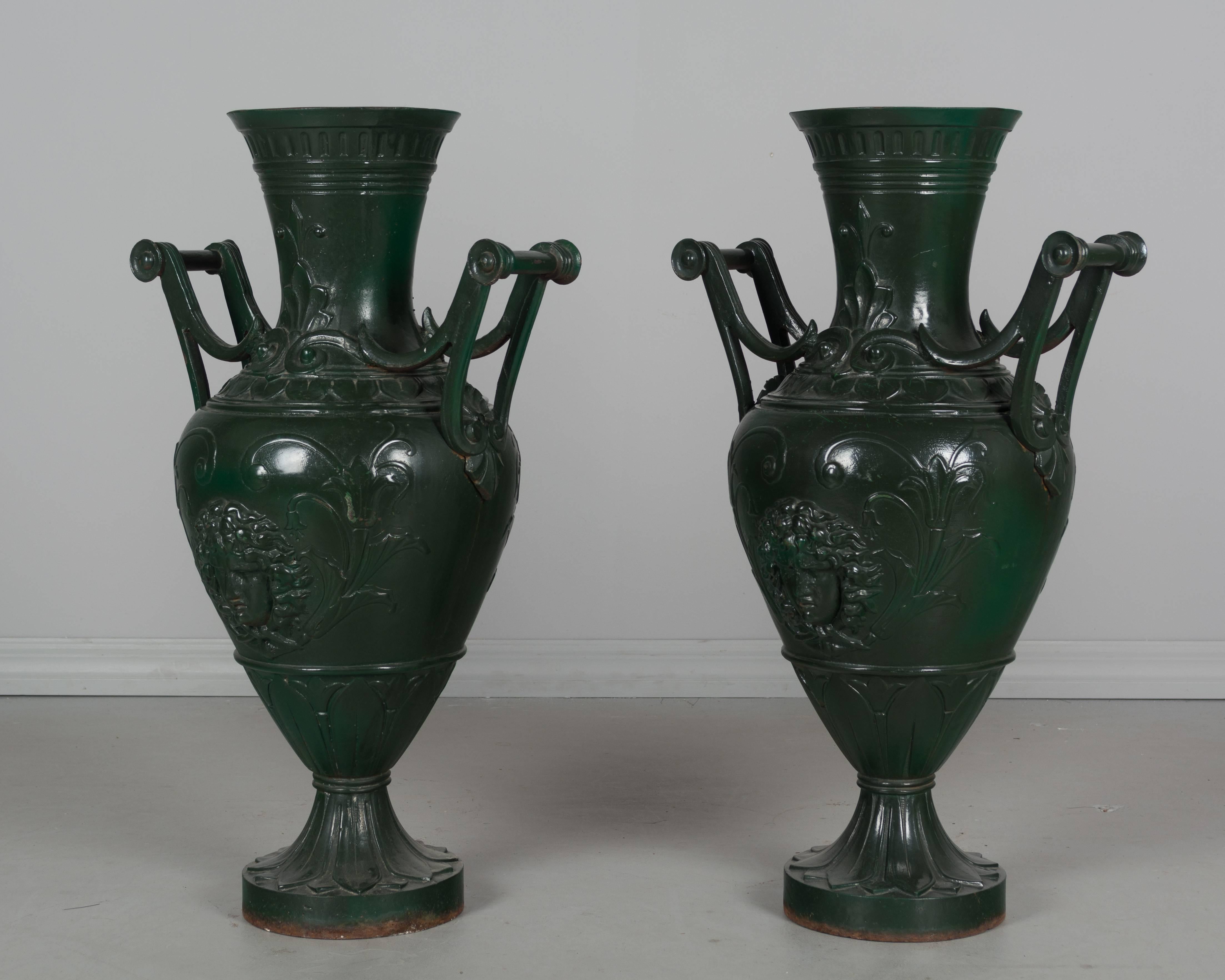 Pair of French Art Nouveau cast iron garden urns with dark green painted patina.  Weight: 90lbs. each
More photos available upon request. We have a large selection of French antiques at Olivier Fleury, Inc. Please visit our showroom in Winter Park,