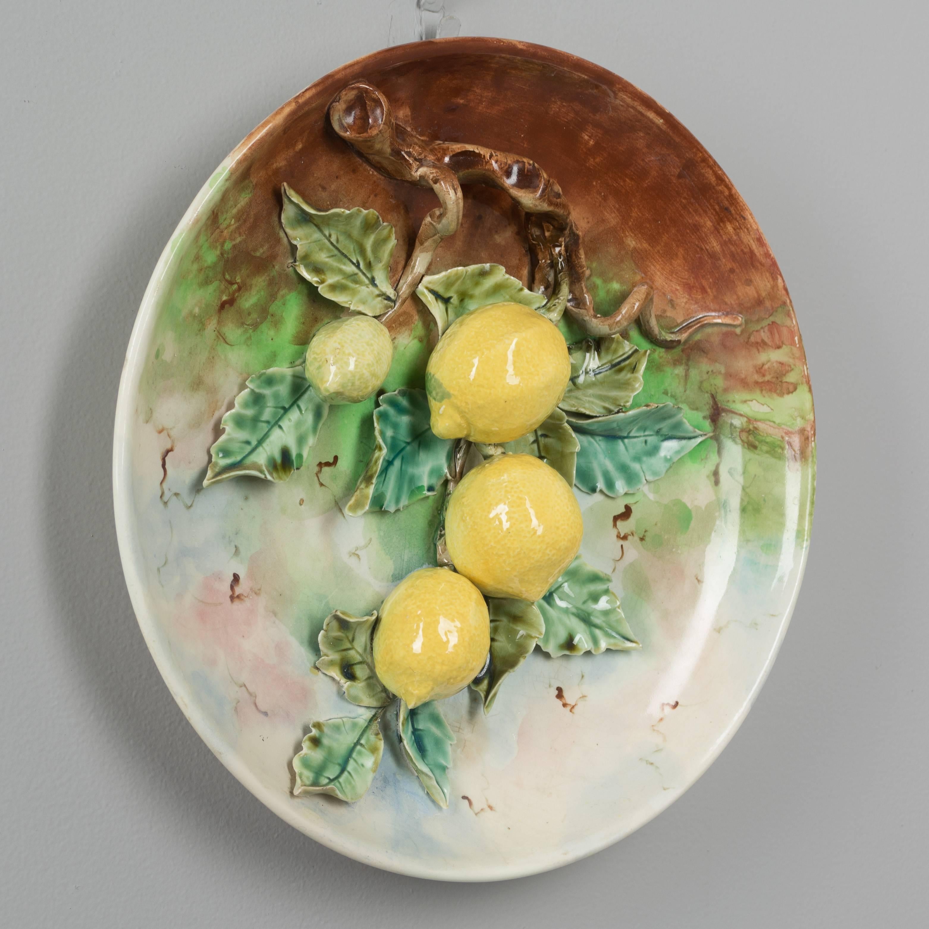 A large 19th century French Barbotine Majolica wall platter with four bright yellow lemons hanging from a tree branch covered with green leaves. Minor loss in one leaf. Sculpted in high relief and hand-painted with vivid color.
We have a large