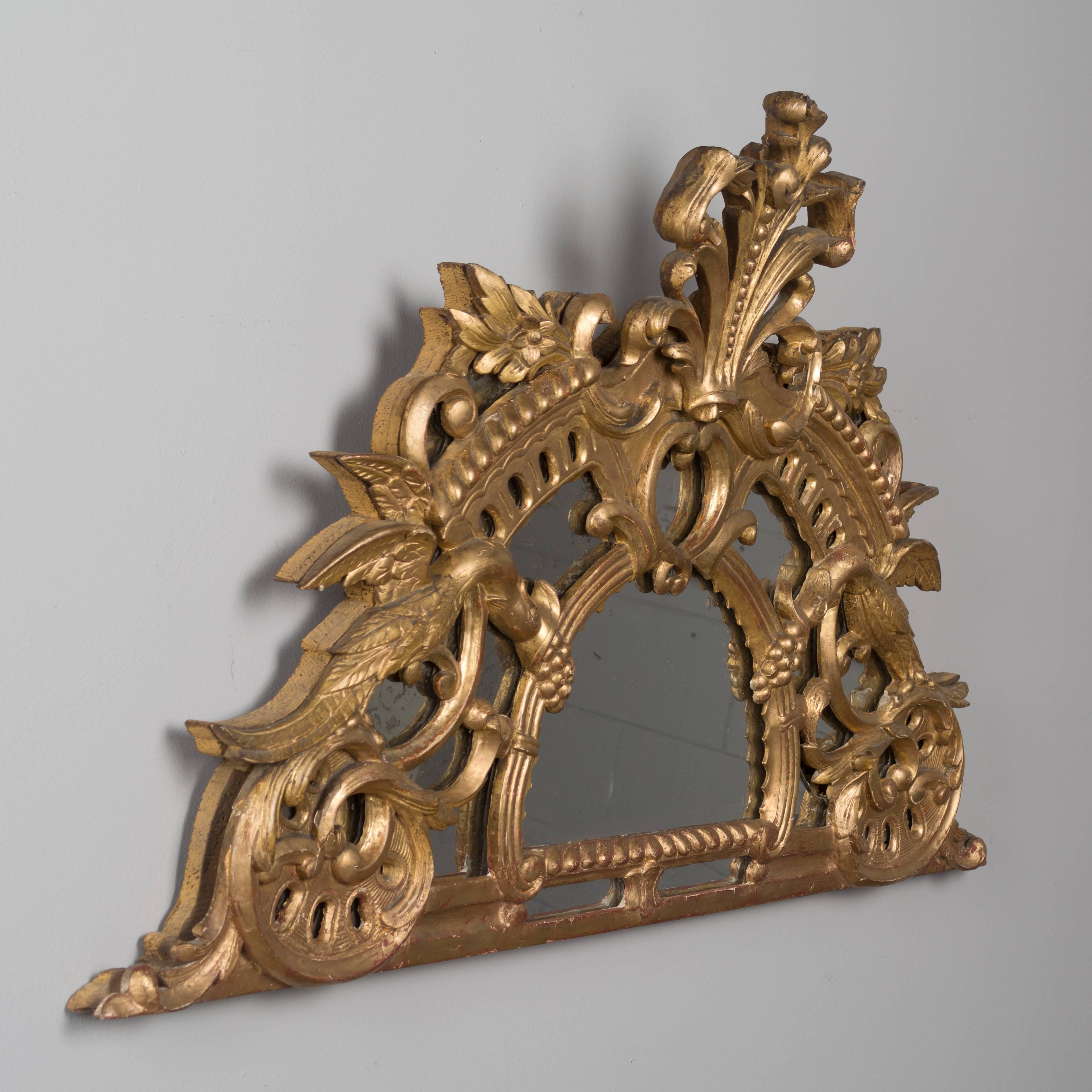 An 18th century French gilt-wood demi-lune mirror. Hand-carved decoration with phoenix flanking each side, acanthus leaves and a tall crest. Original mirror with old silvering. Bright gilt has been touched up but is in very good condition for the