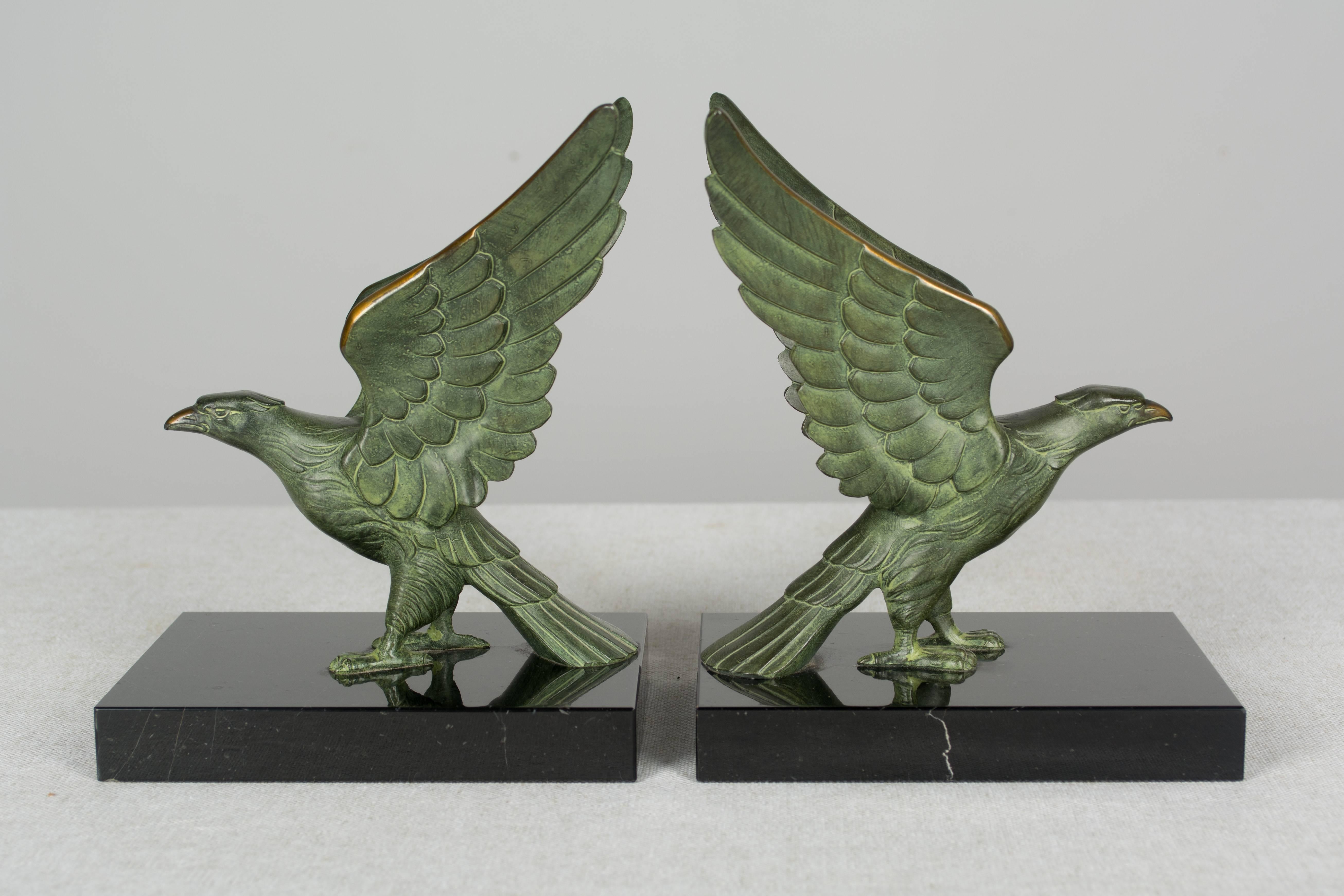 A set of French Art Deco cast bronze falcon bookends on black marble base. Beautiful green patina with polished golden highlights on the beak and wings. More photos available upon request. We have a large selection of French antiques at Olivier