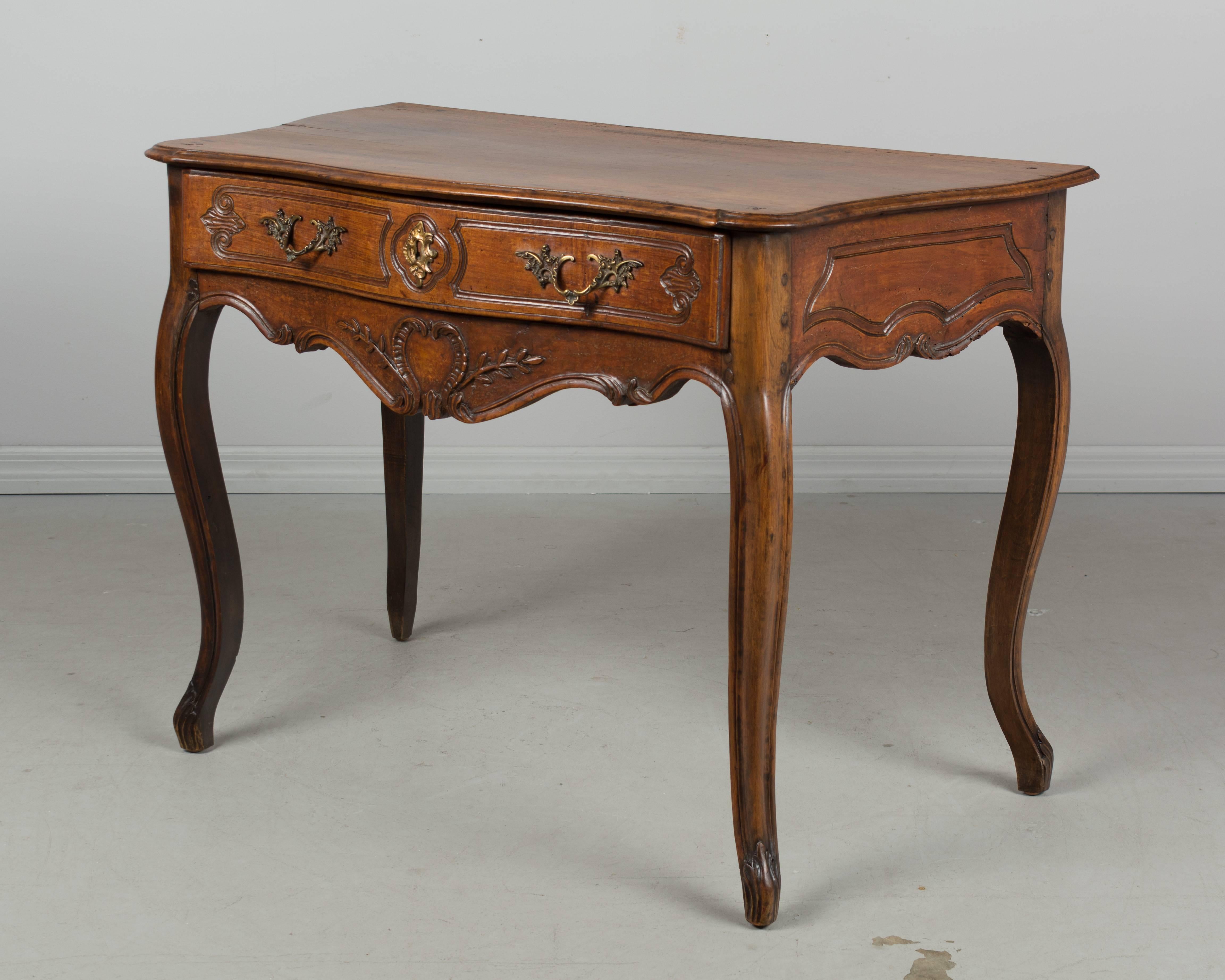 A 19th century Louis XV style French Provençal console table with serpentine front, curved sides and a single dovetailed drawer. Made of solid walnut with nice hand-carved details. The bronze hardware is as found. Nice proportions, sturdy and well