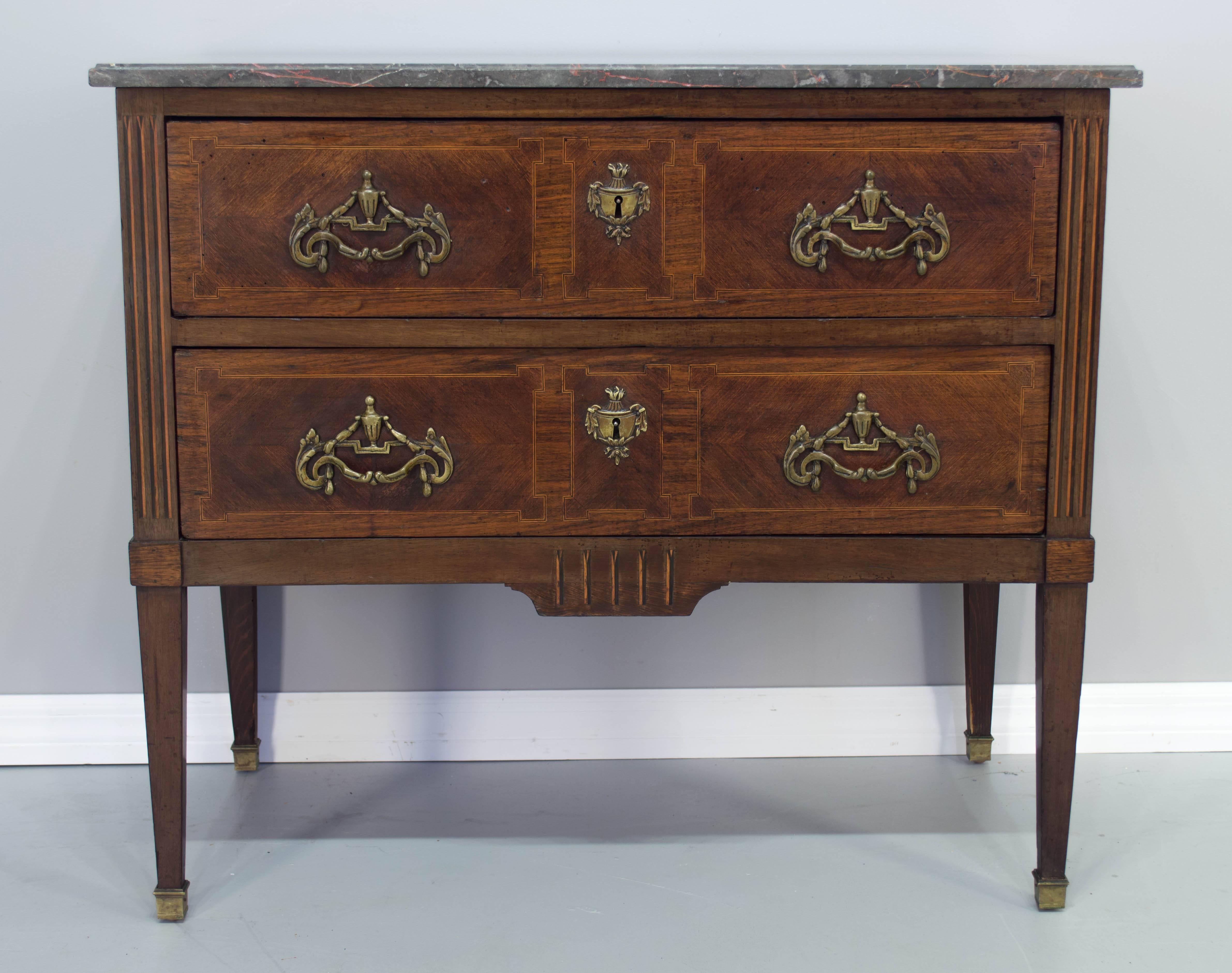 An early 19th century Louis XVI style commode with two dovetailed drawers, mahogany with nice inlay detail, original bronze hardware and sabots. Grey veined marble top. Locks are present but no keys. A good size for use as a side table or night