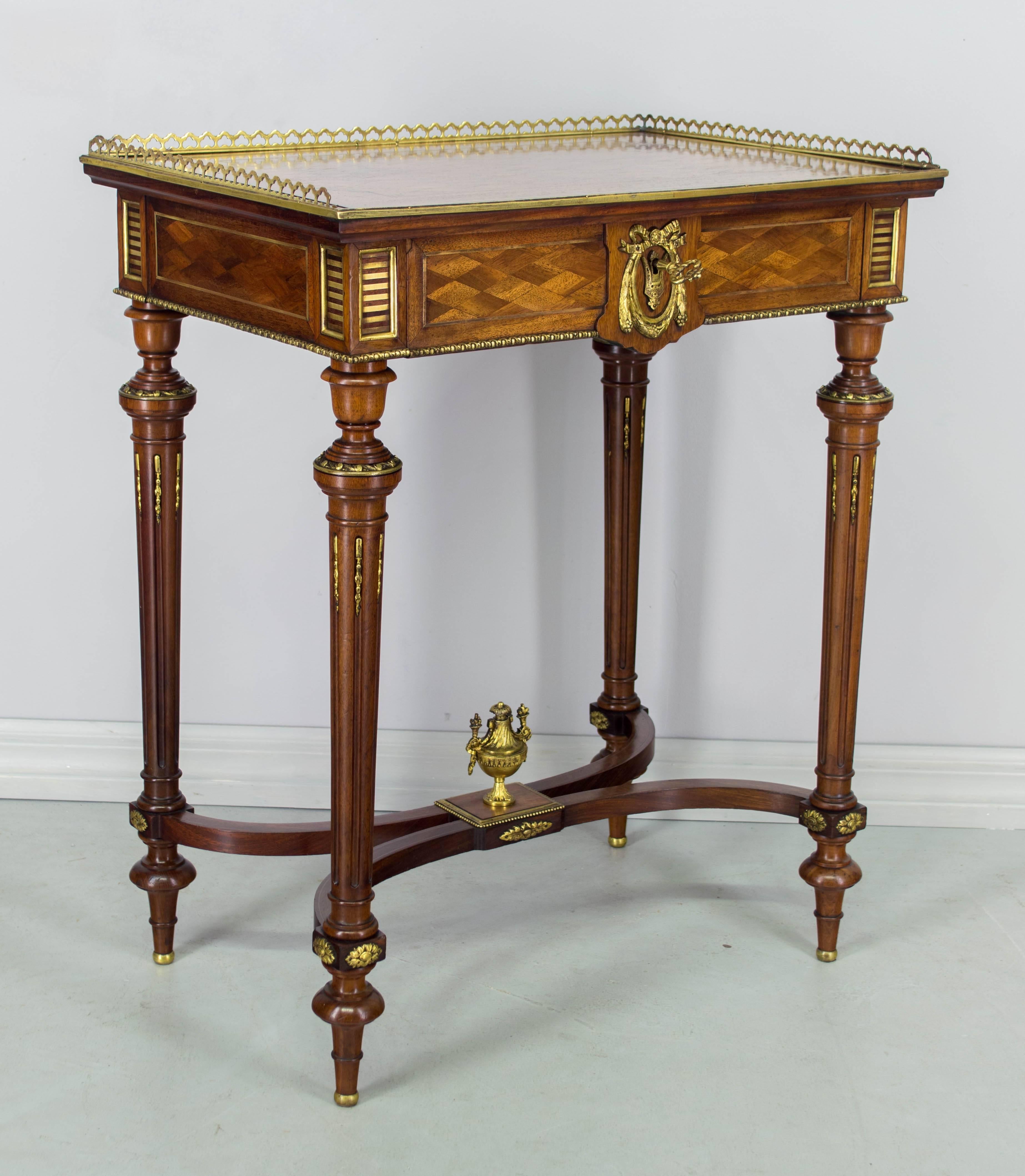 A superb Napoleon III bronze-mounted travailleuse, or "work table" with hinged top. Solid mahogany with parquetry mahogany veneer top and sides and inlaid bronze details. Bronze gallery and delicate decoration. Top opens to reveal a