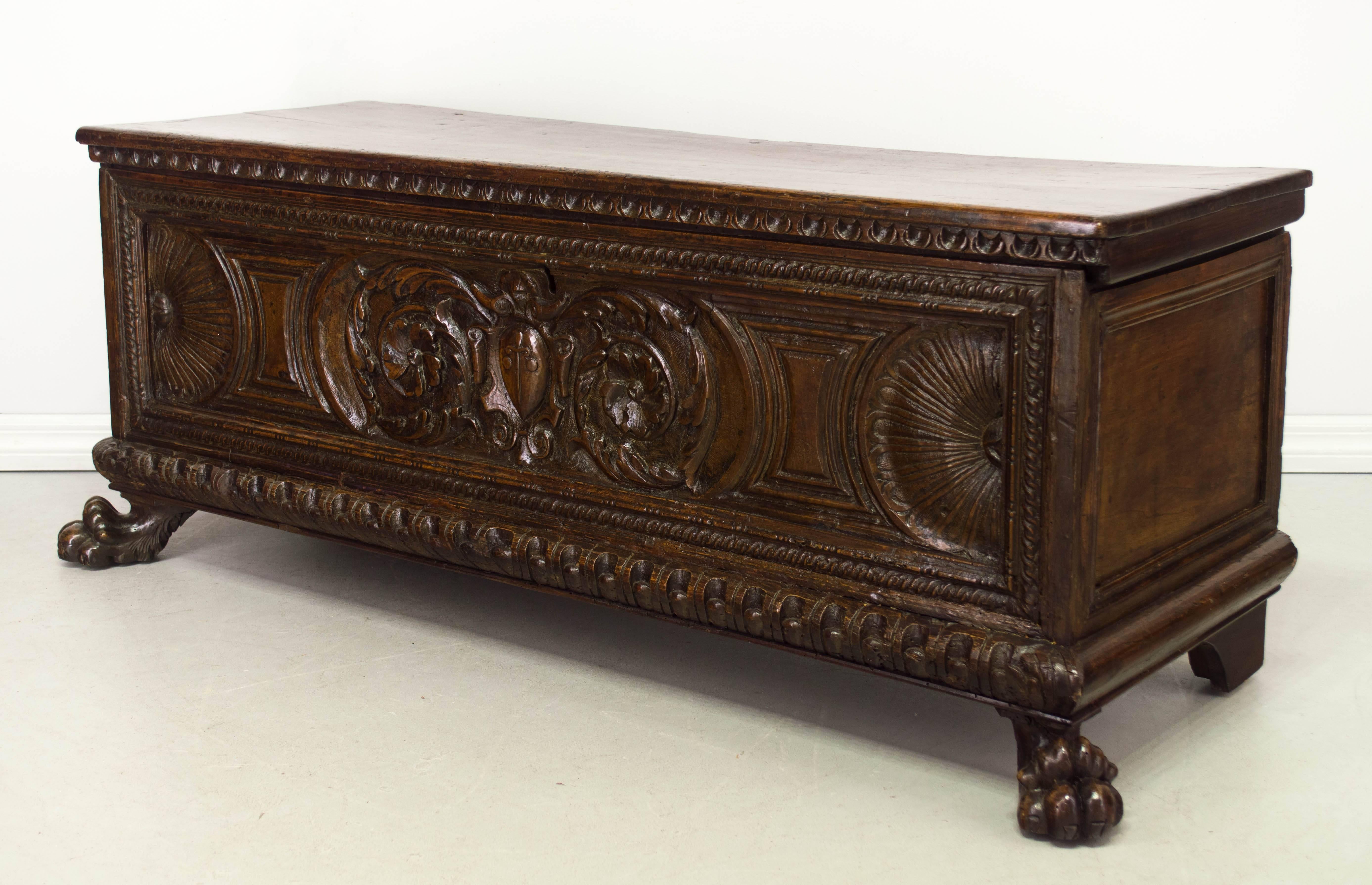 18th century Italian cassonne or chest made of solid walnut with decoration carved in low relief. Large lion paw feet in front. Lock, but no key. Waxed patina. Restoration on back legs and hinges. We have a large selection of French antiques. Please