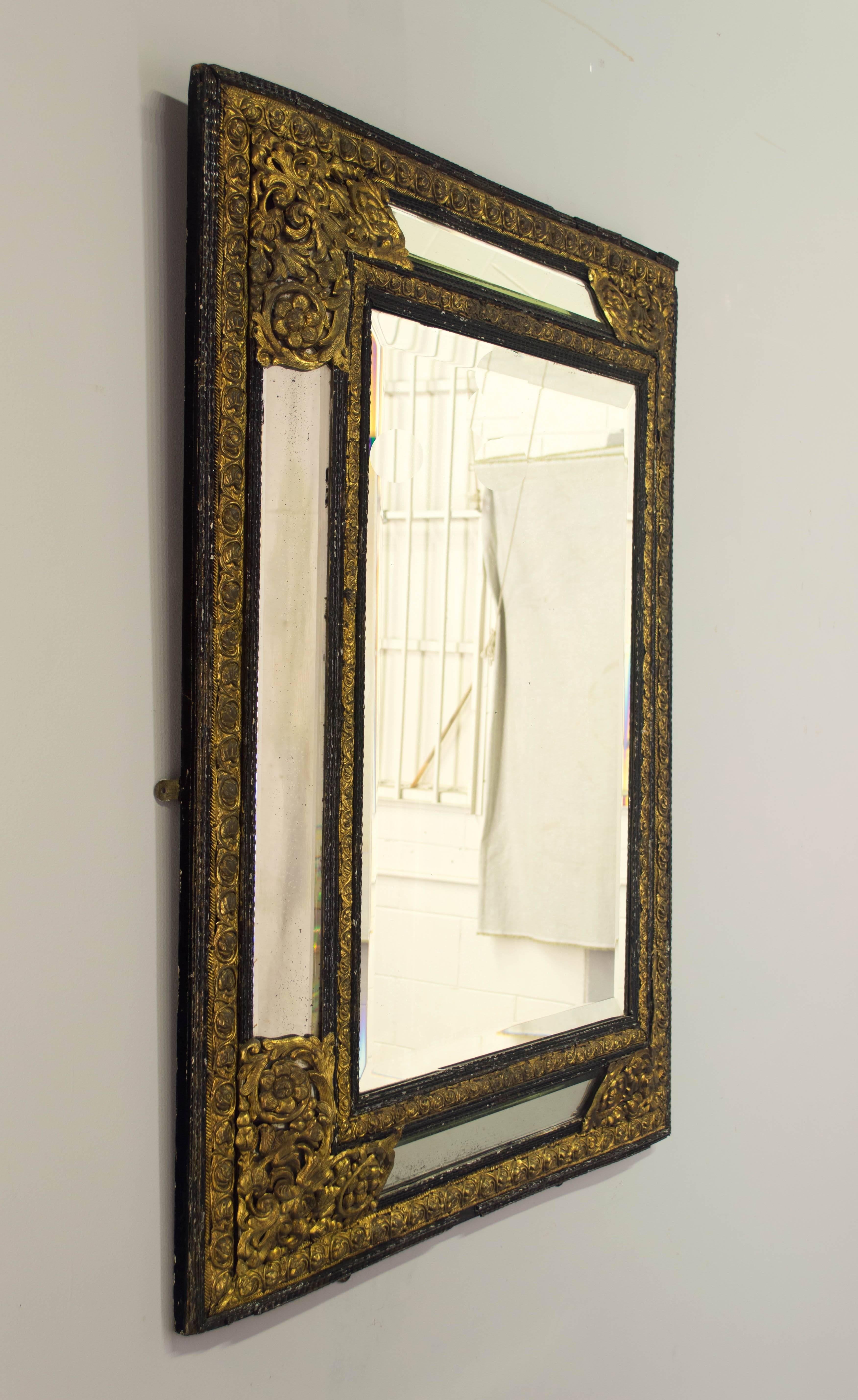 19th c. Dutch mirror with elaborately detailed brass embossed and ebony trim. Original beveled mirror. Missing some pieces of trim. We have a large selection of French antiques. Please visit our web site.