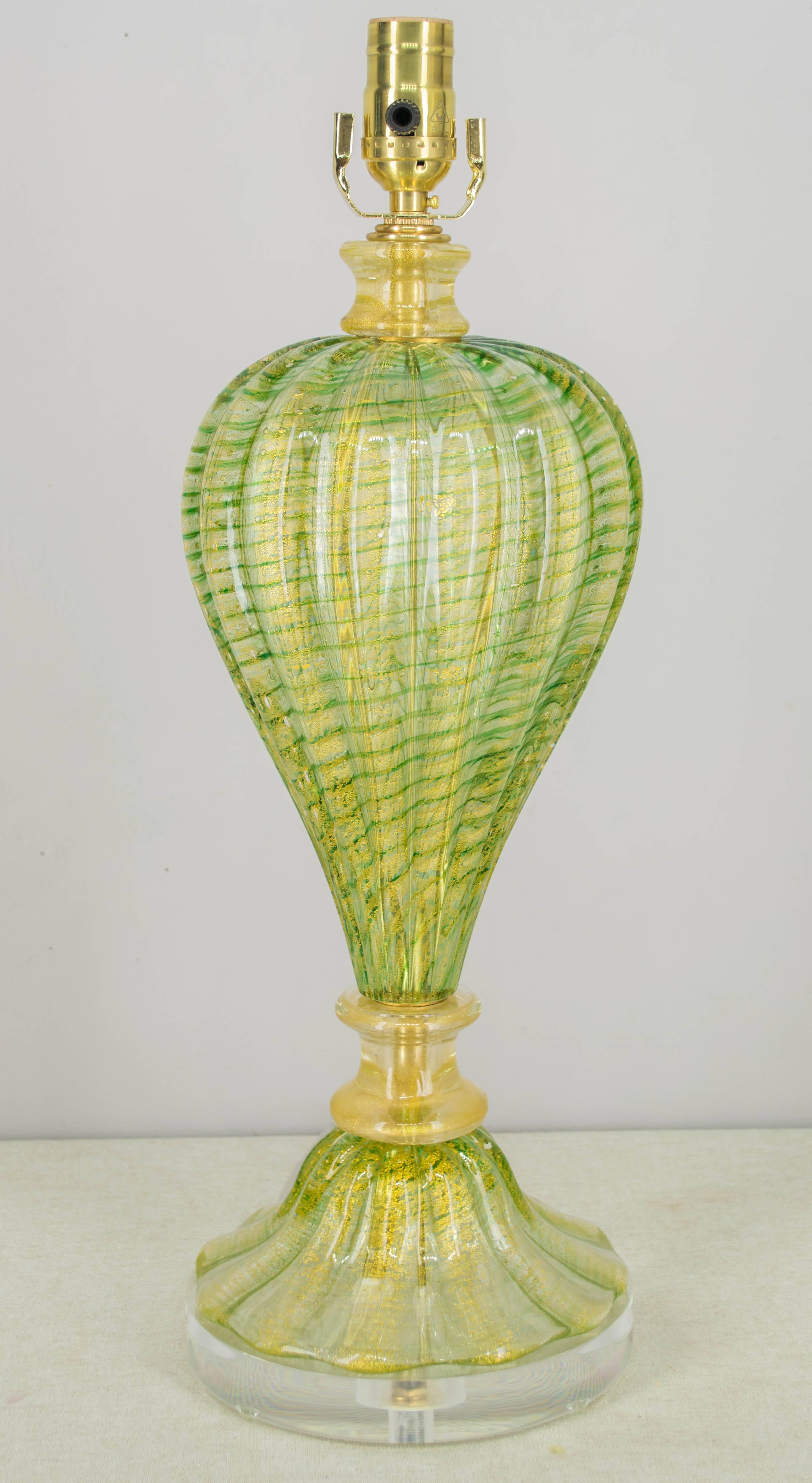 Murano glass lamp in beautiful shade of apple green with gold inclusions. Handblown in four separate parts. Rewired, new sockets and clear lucite base. White linen drum shade not included, but dimensions are 14" diameter x 10"