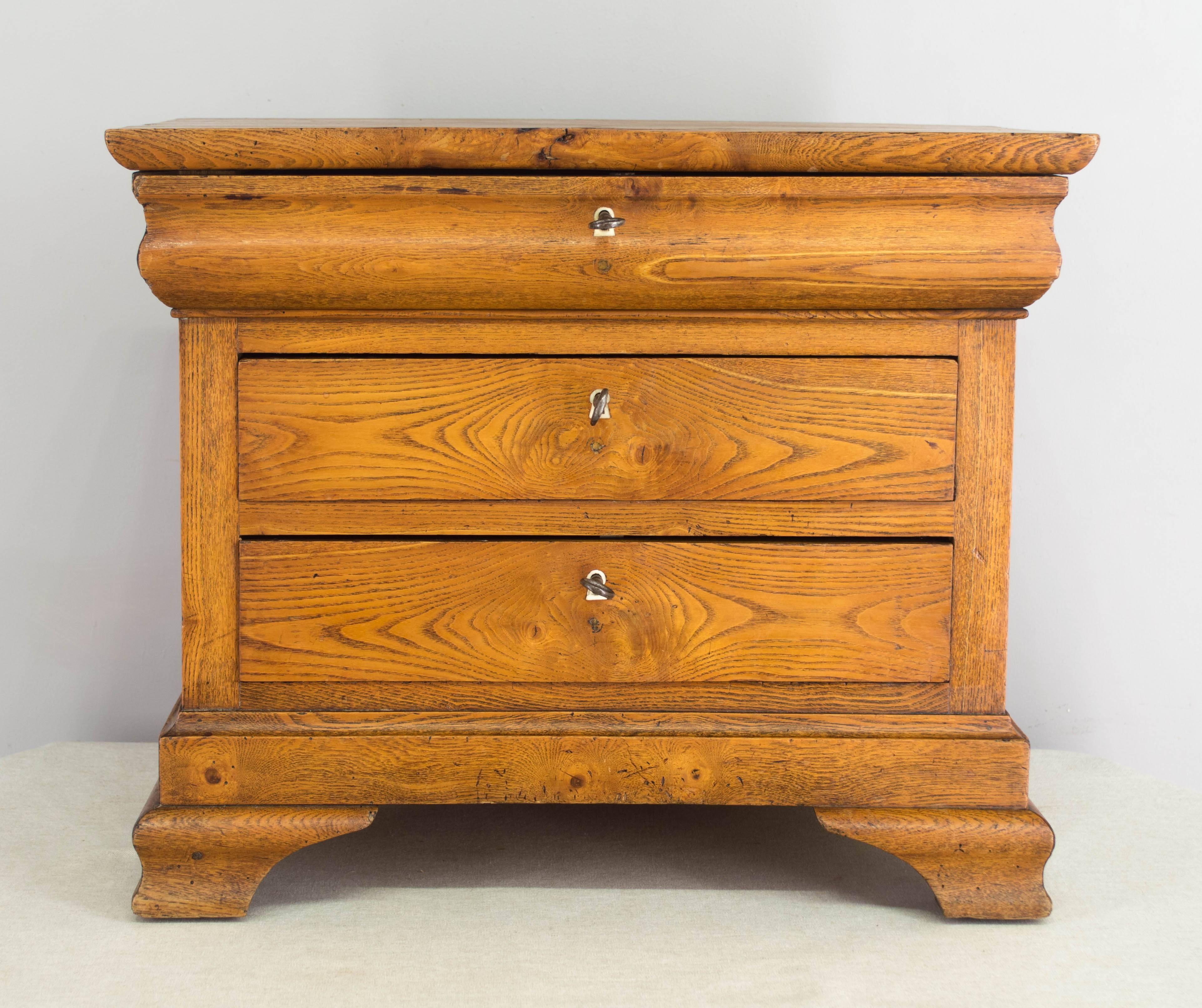 A superb 19th century Louis Philippe style miniature commode made of elmwood. Three dovetailed drawers with locks and keys in working order. Beautiful character to the wood, with knots and swirling pattern to the grain. Unusually large size and